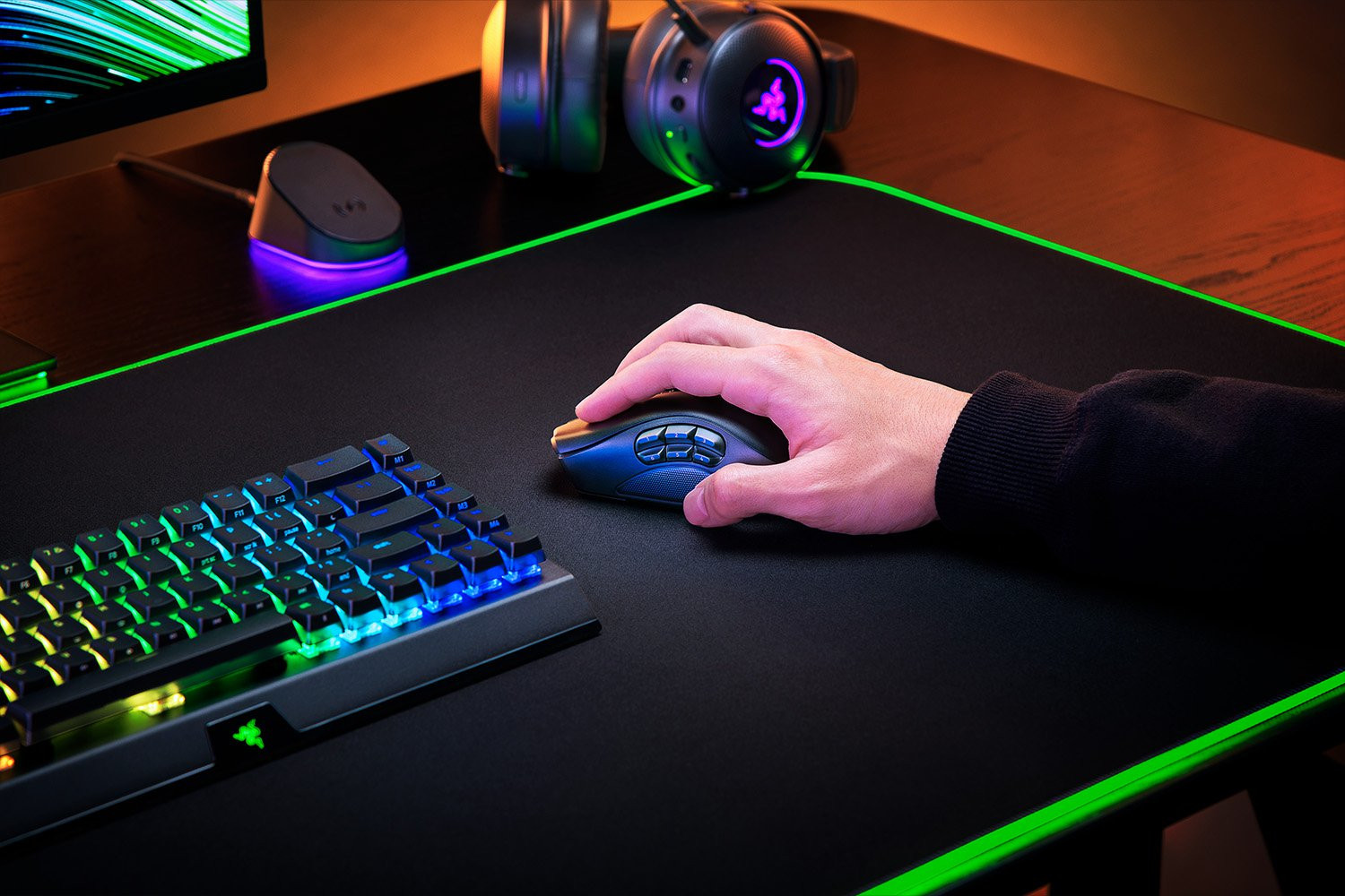 Hand met zwarte gamingmuis op zwart muismat met RGB.