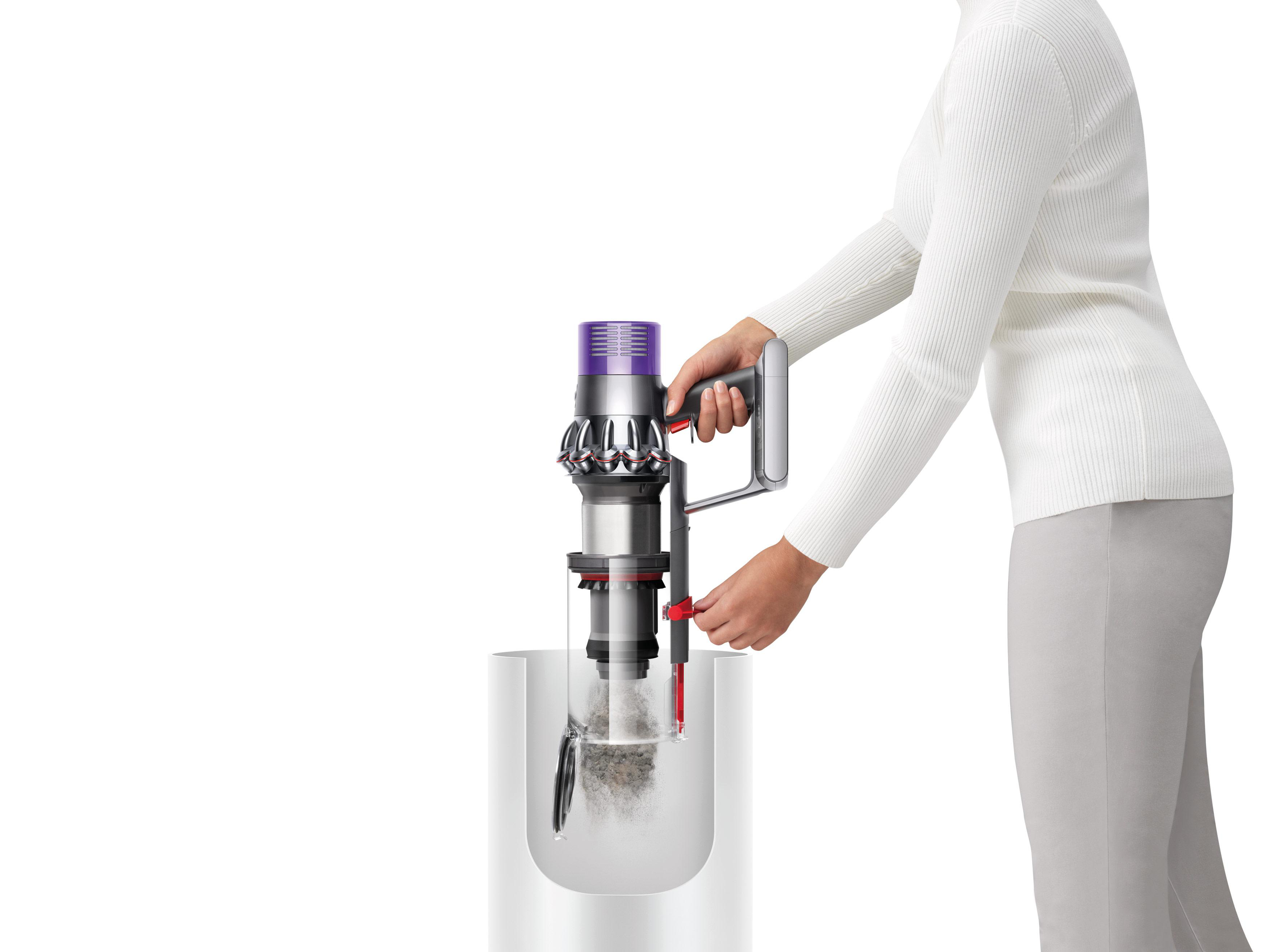 Eine Person benutzt einen Dyson-Staubsauger und leert einen Behälter.