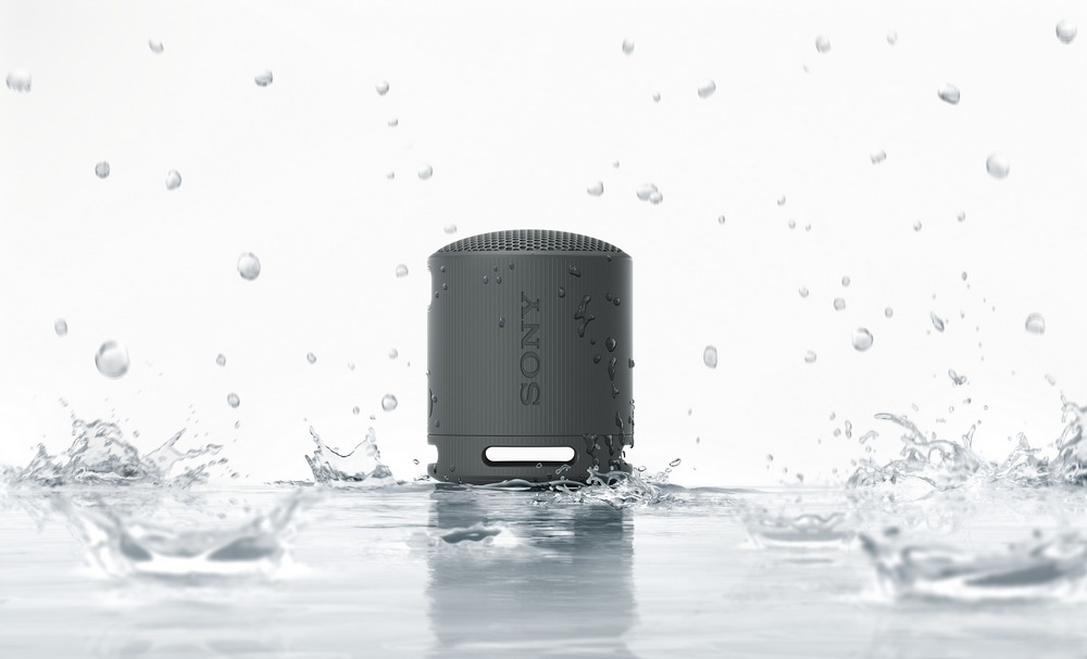 Un pequeño altavoz gris con salpicaduras de agua alrededor, marca Sony visible.