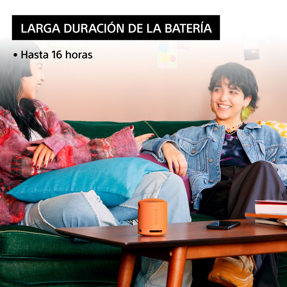 Dos mujeres sentadas, sonriendo, con un pequeño altavoz naranja. Texto: Larga duración de la batería.