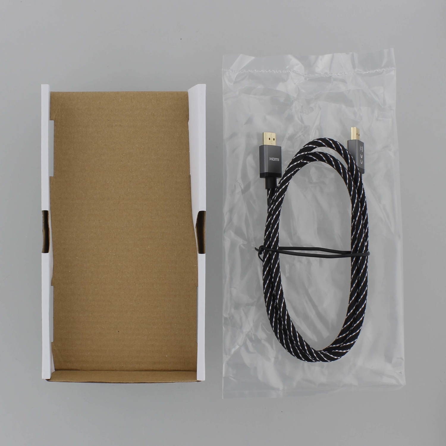 Cable HDMI en una bolsa de plástico transparente, con una caja de cartón al lado.