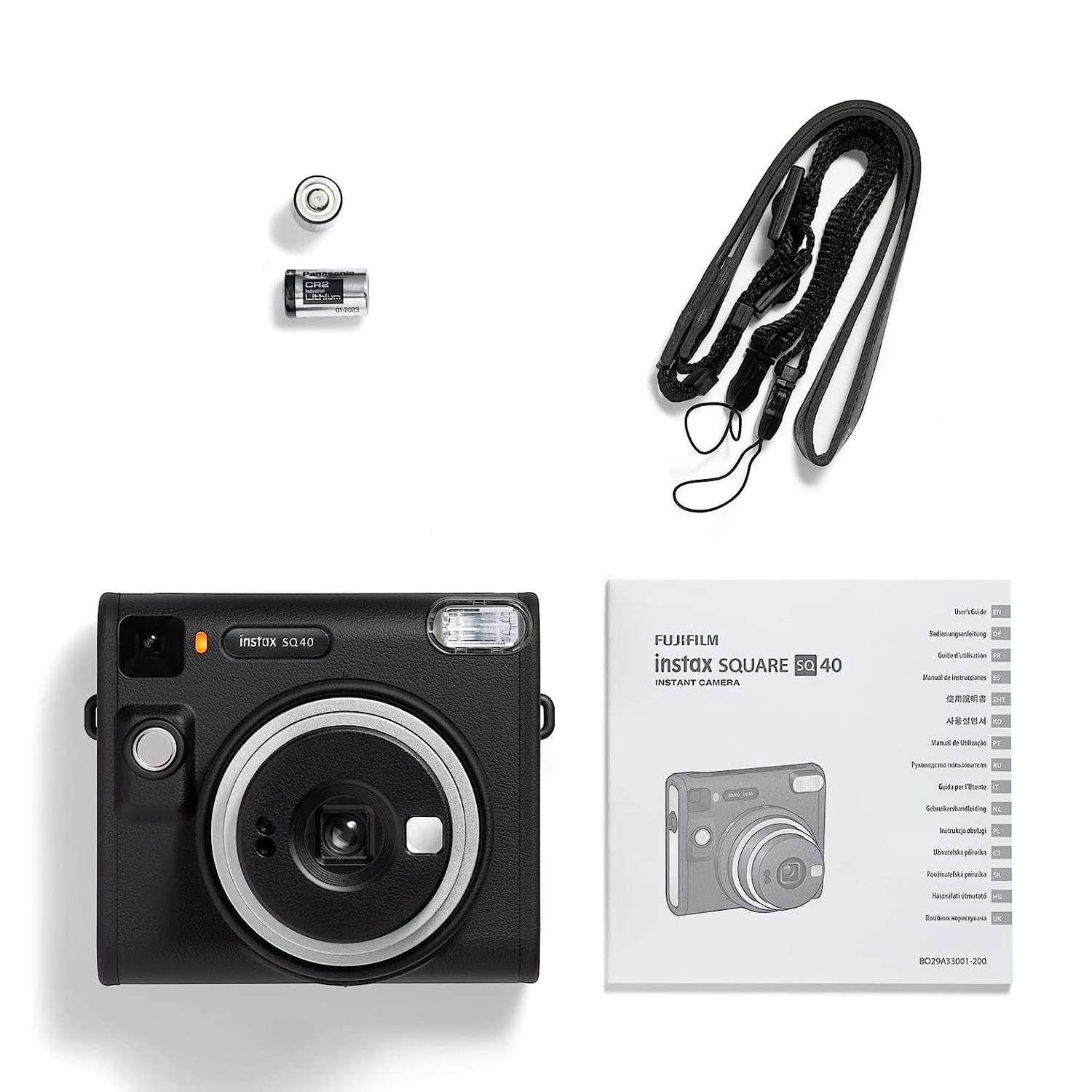 Fotocamera Instax nera con accessori: cinturino, batterie e manuale. Sfondo bianco.