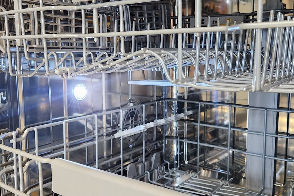 Widok wewnątrz zmywarki, pokazujący kosze i ramiona natryskowe.