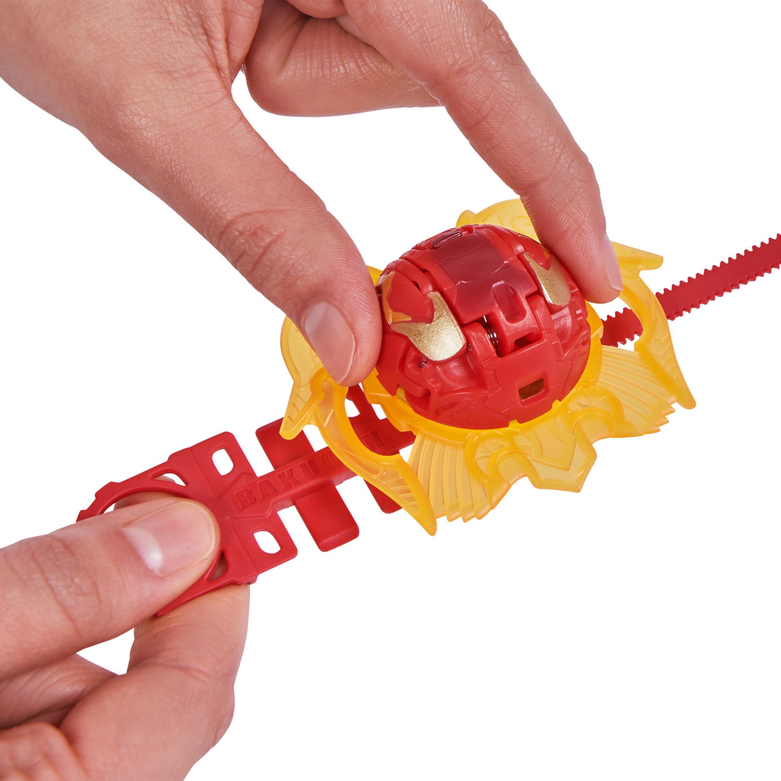 Zwei Hände halten ein rotes und gelbes Bakugan-Spielzeug mit rotem und gelbem Zubehör.