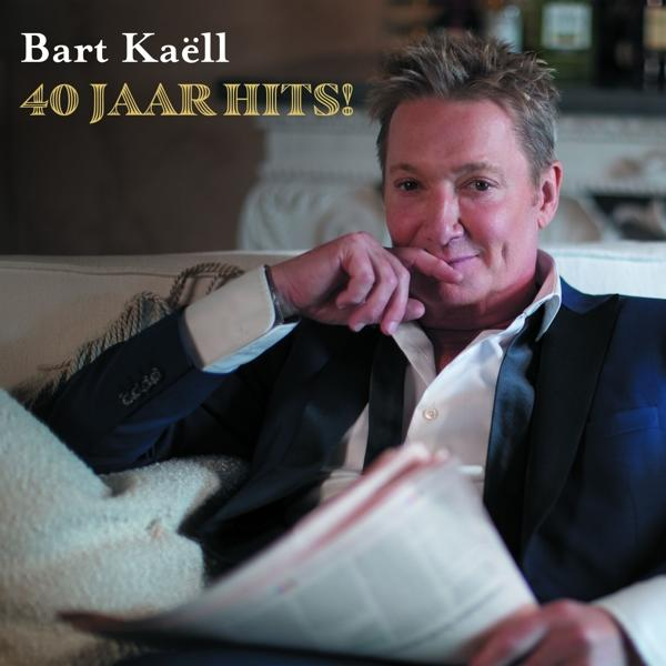 Bart Kaëll sur un canapé, tenant un journal. Le titre est 40 Jaar Hits !