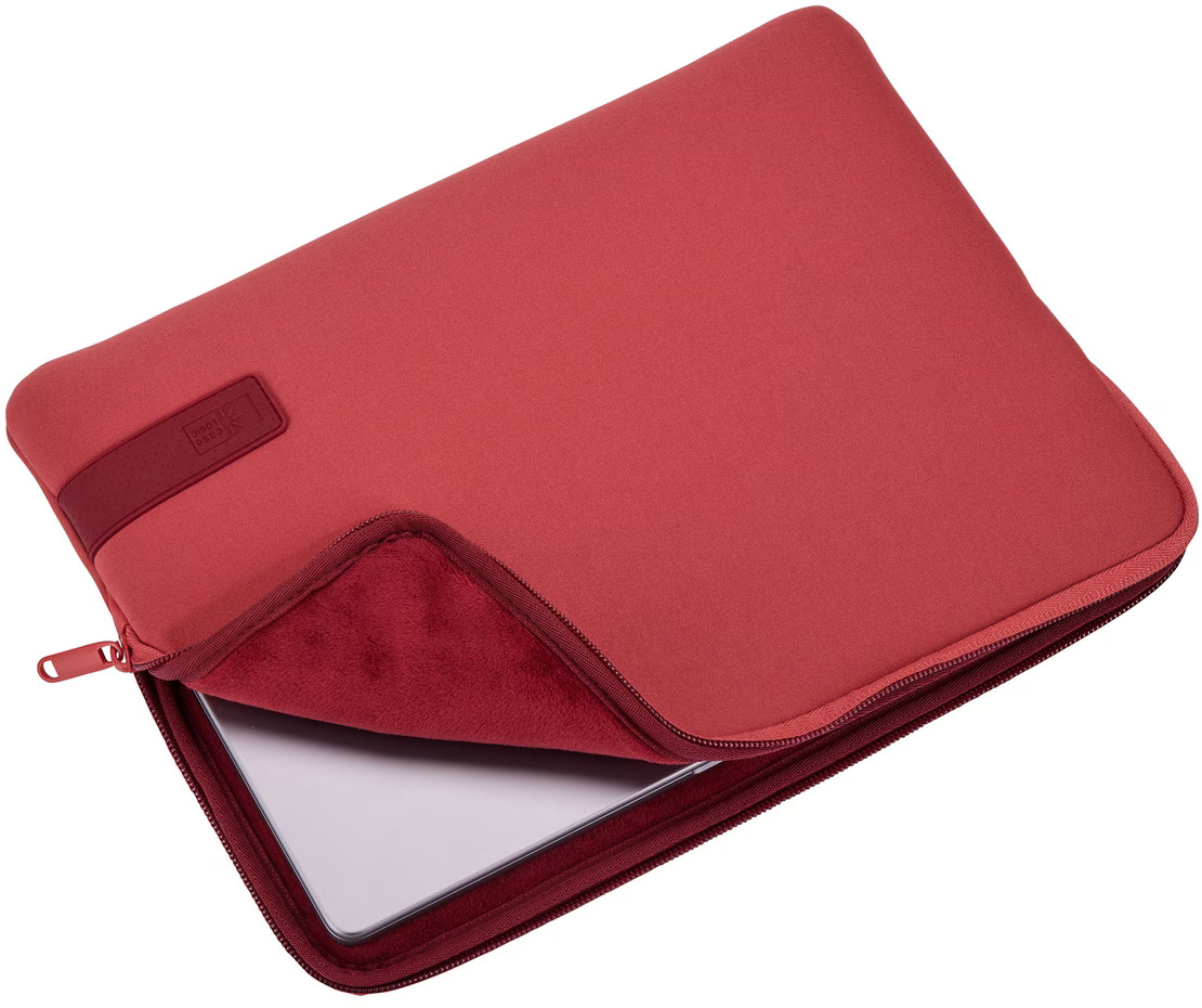 Housse d'ordinateur portable rouge avec une fermeture éclair. Un ordinateur portable est partiellement visible.