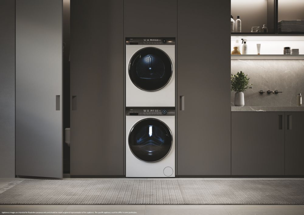 Deux machines à laver Haier blanches empilées, dans une buanderie sombre et moderne.