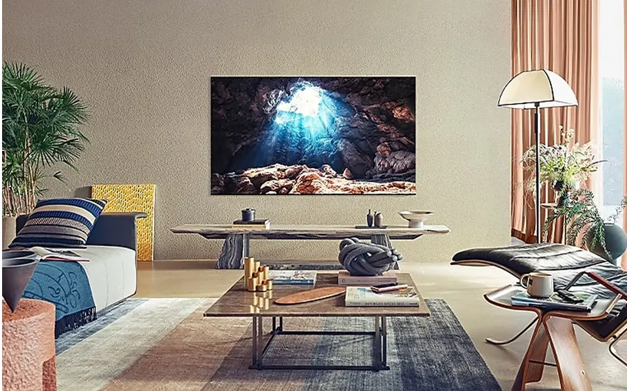 Une grande télévision affichant une grotte avec la lumière du soleil dans un salon moderne avec une table basse et un canapé.