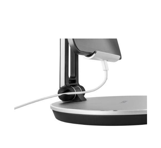 Ein Telefon steht auf einem Ständer und wird über ein weißes Kabel aufgeladen. Der Ständer ist silber und schwarz.