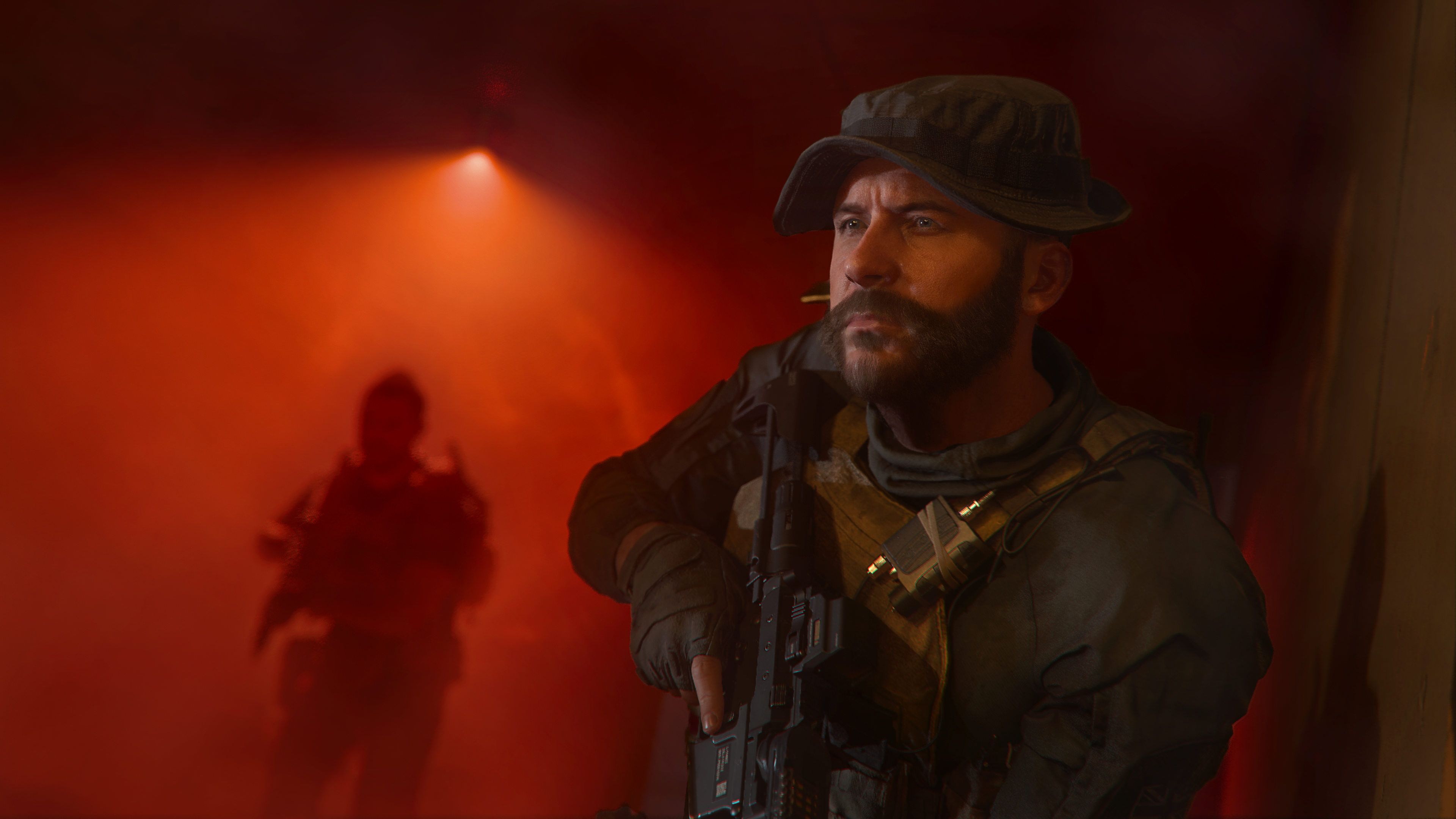 Mann in Militäruniform schaut zur Seite, rote Beleuchtung. Eine weitere Figur unscharf.