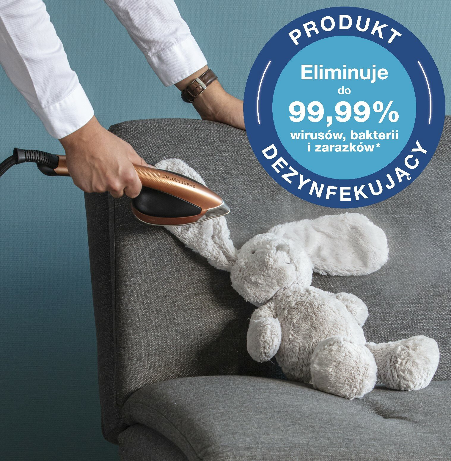 Osoba paruje pluszowego króliczka na kanapie za pomocą parownicy do ubrań.