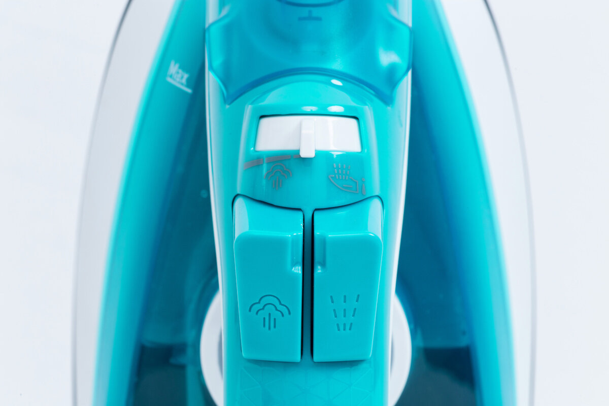 Zbliżenie turkusowego żelazka z przyciskami sterowania. Jest na białym tle.