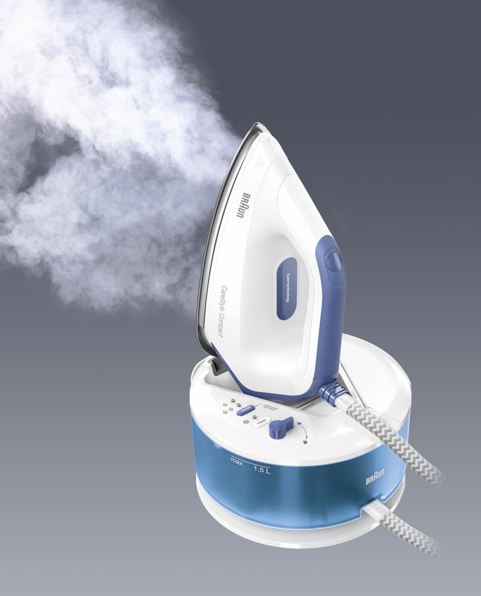 Biało-niebieskie żelazko parowe Braun z parą, na podstawie, skierowane w górę.