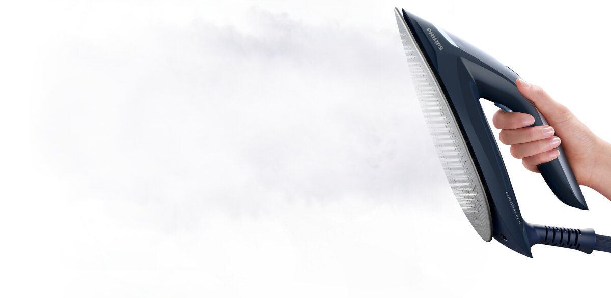 Ręka trzymająca niebieskie żelazko z parą na białym tle.