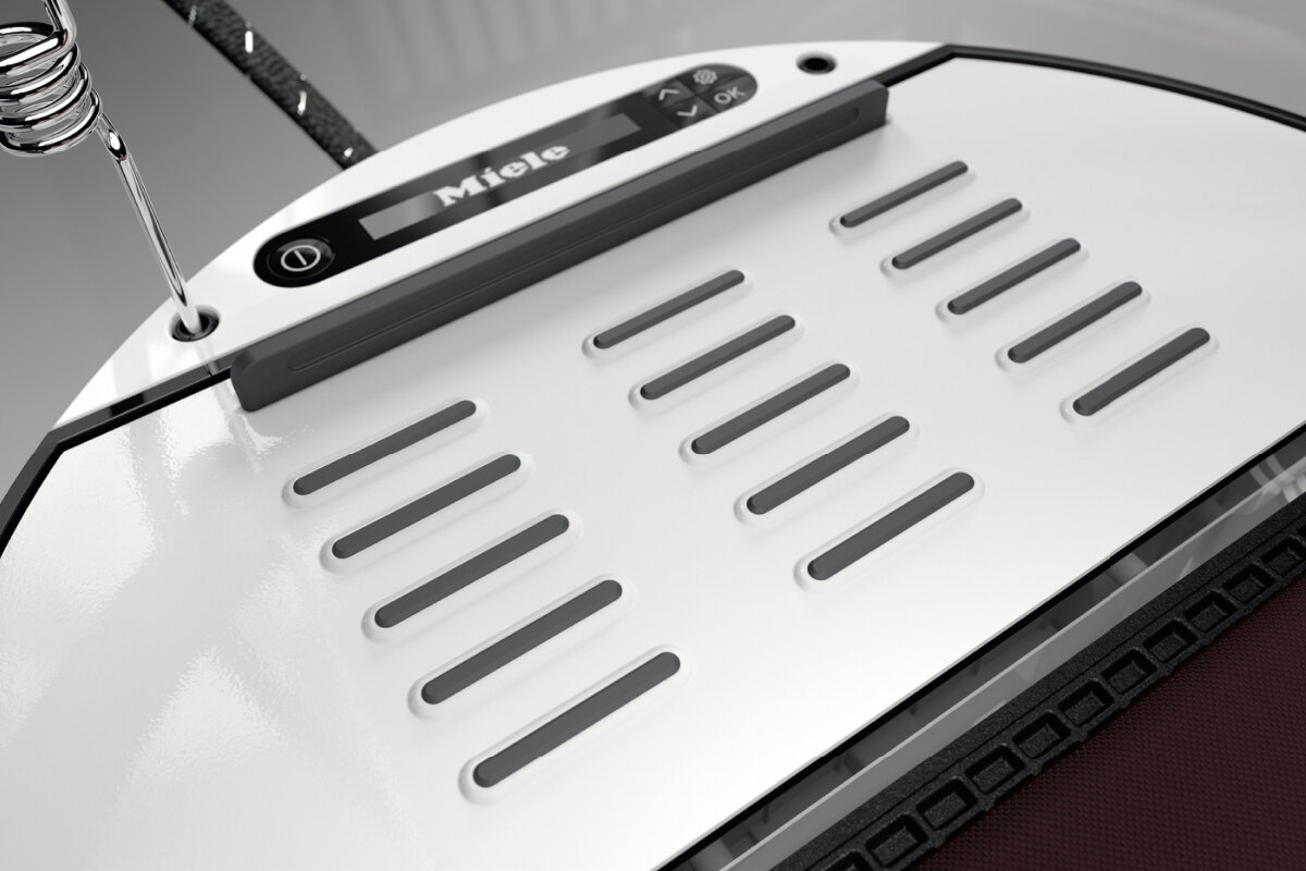 Białe i srebrne żelazko z logo Miele, zbliżenie.