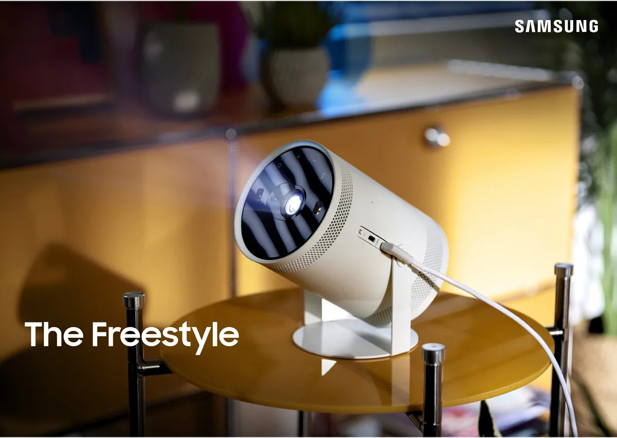 Un proiettore cilindrico bianco su un supporto, che proietta luce, con la scritta "The Freestyle".