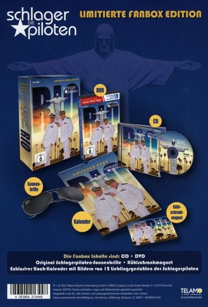 Boxset mit CDs, DVDs, Kalender und Sonnenbrille. Jesus-Statue im Hintergrund.