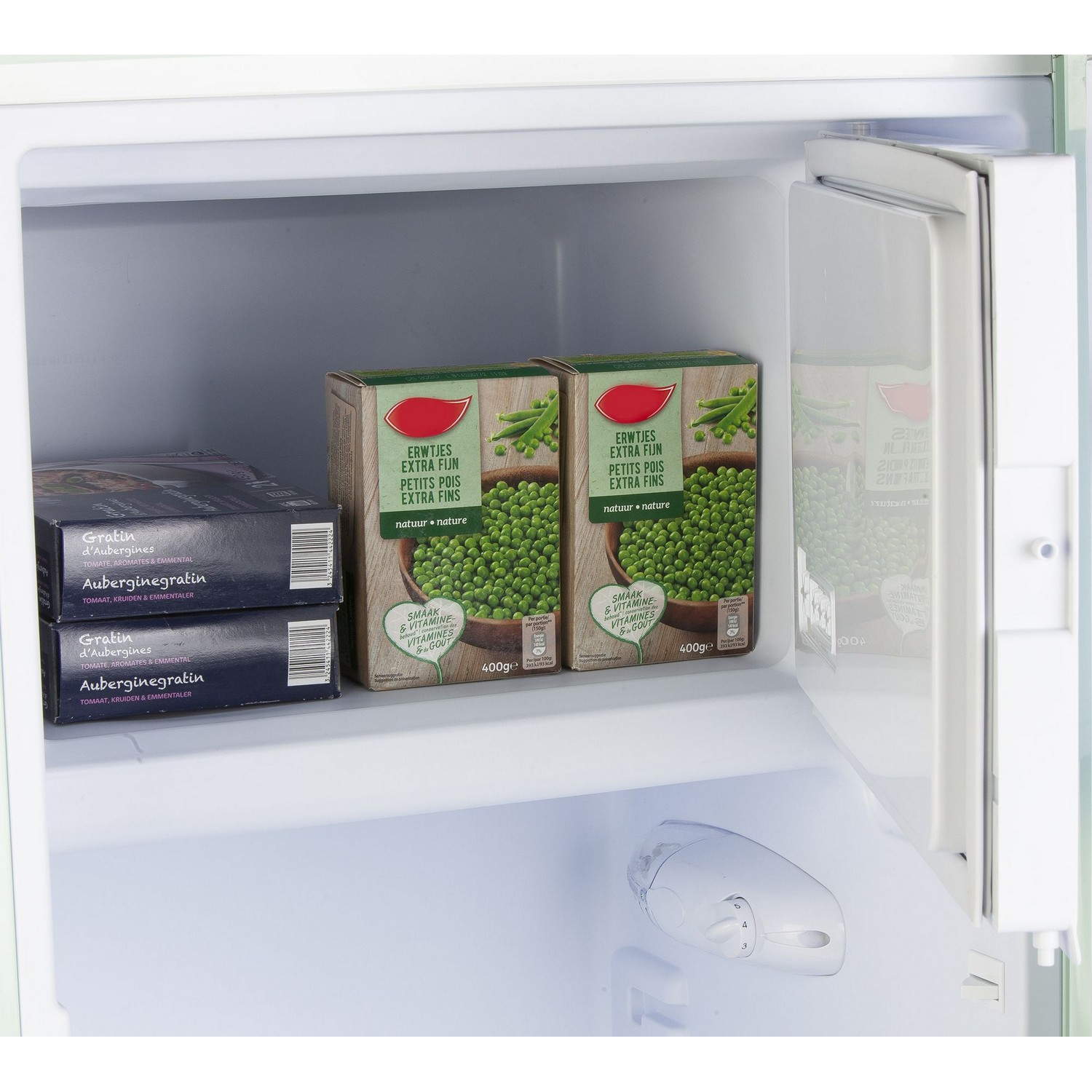Réfrigérateur ouvert avec des paquets d'aliments surgelés, petits pois et gratin d'aubergines.