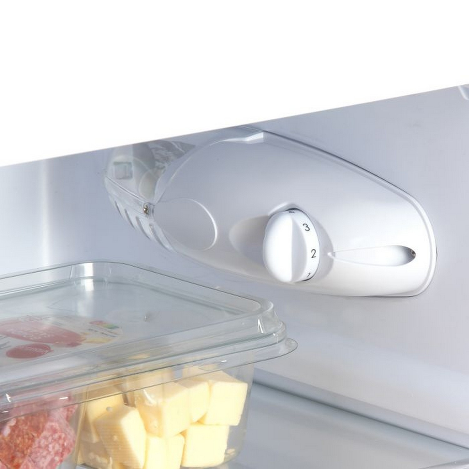 Refrigerator interior with shelves, food, and a control dial. There are butter and other items.