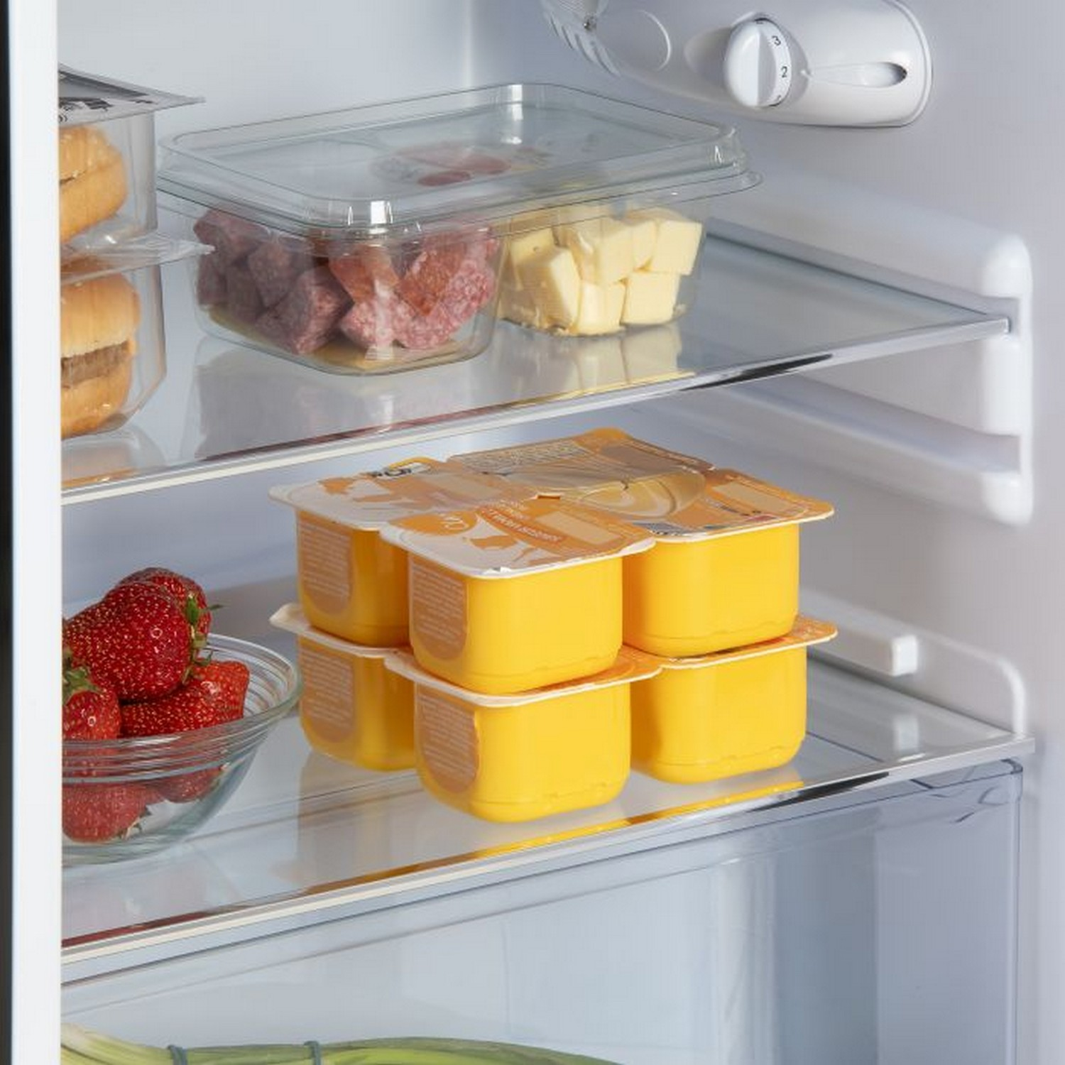 Inside a fridge with food items: strawberries, cheese, yogurt, and other packaged items.