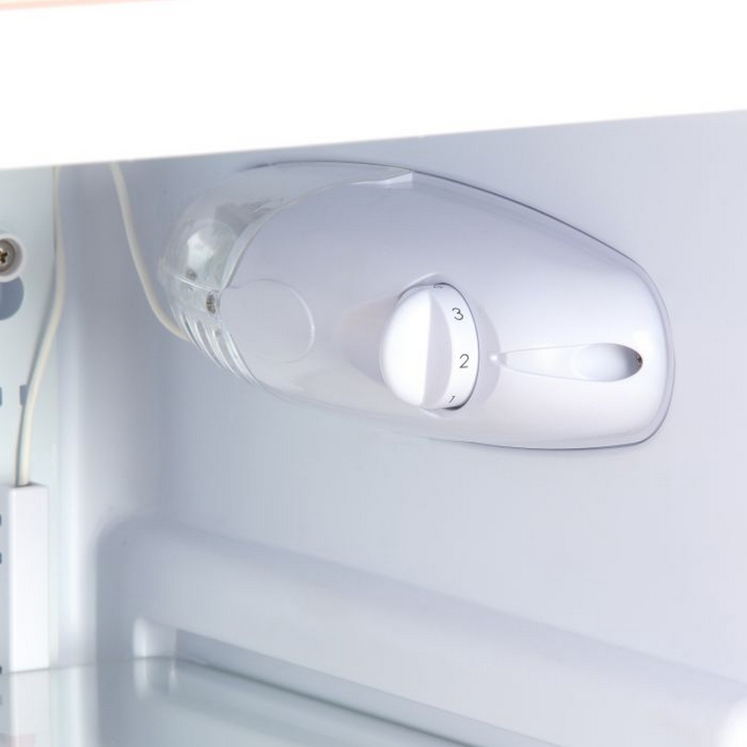Inside a refrigerator, a white control with a dial numbered 1-3.