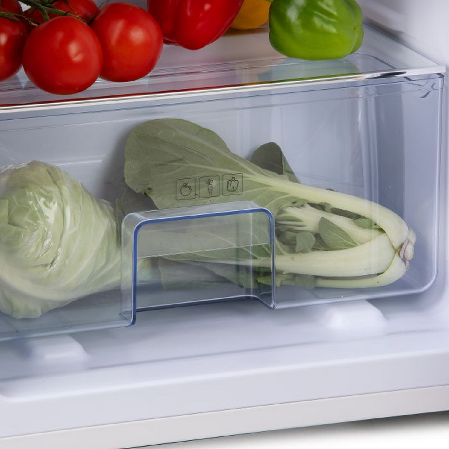 Réfrigérateur ouvert avec des légumes dans le bac à légumes. Chou et légumes-feuilles verts visibles.
