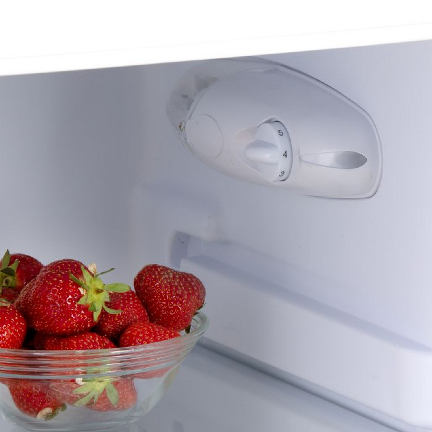 Fraises dans un bol en verre dans un réfrigérateur avec cadran.