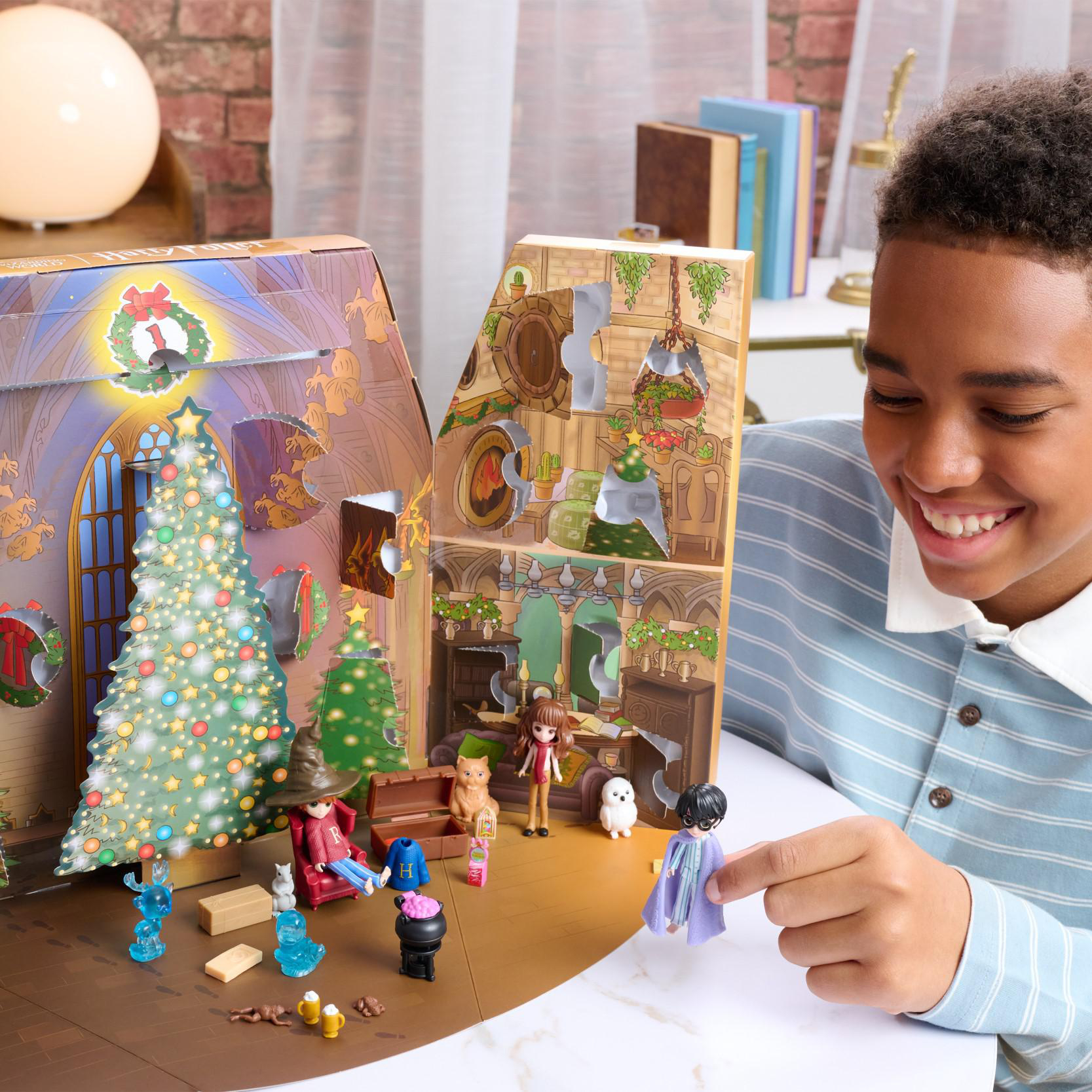 Ein Junge spielt mit einem Harry Potter Adventskalender. Die Szene umfasst Figuren, einen Baum und ein Schloss.