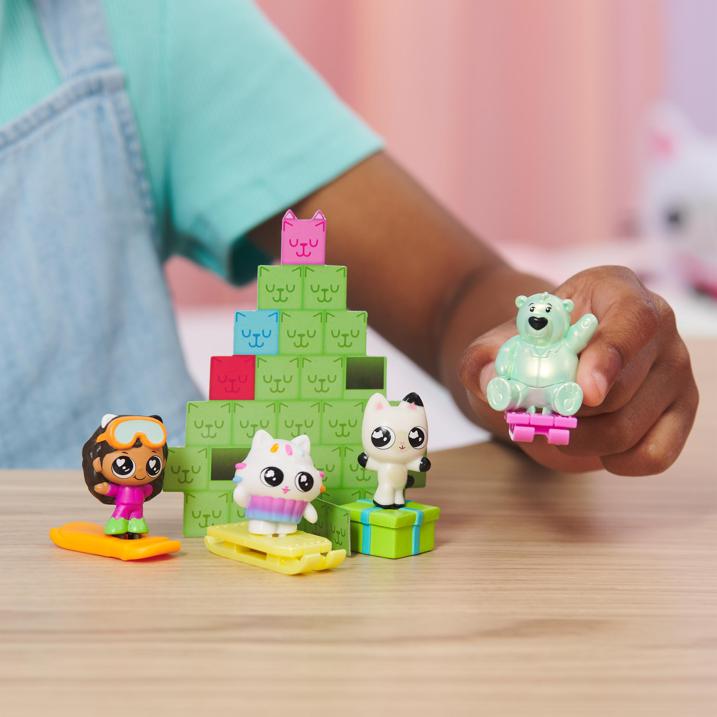 Kinderhand mit Spielzeug: Katzen und ein Bär auf einem Tisch.