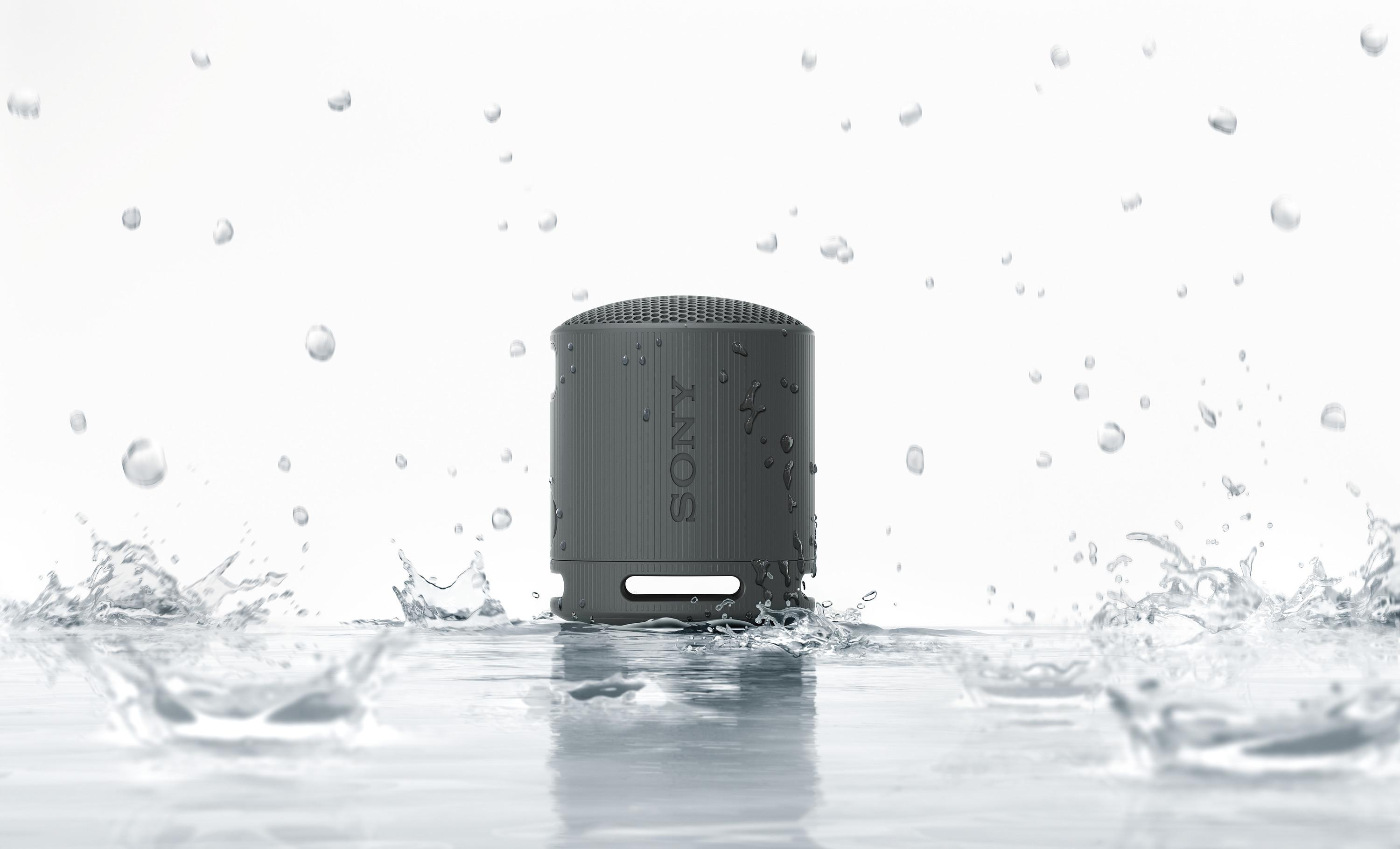 Grauer Sony-Lautsprecher im Wasser mit Spritzern auf Weiß.