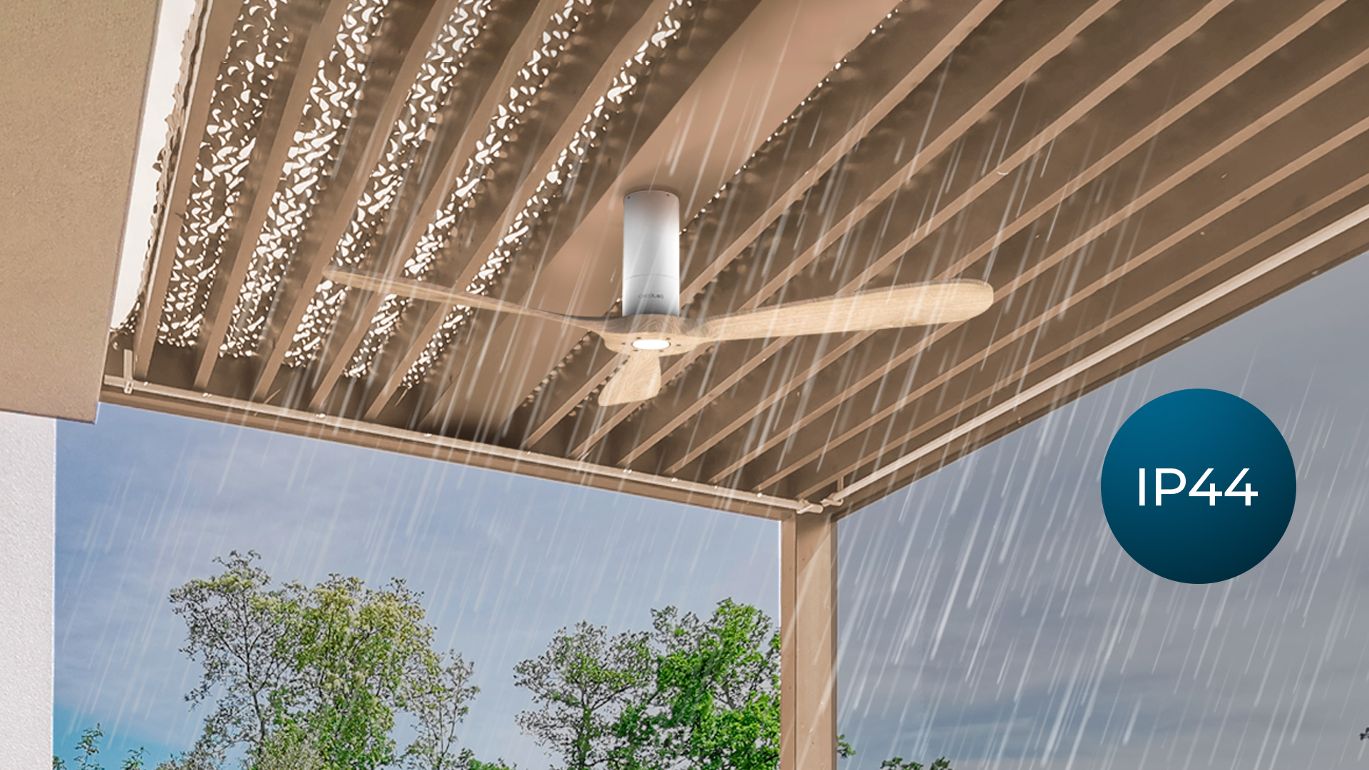 Un ventilador de techo blanco bajo la lluvia, instalado bajo una pérgola con la clasificación IP44 visible.