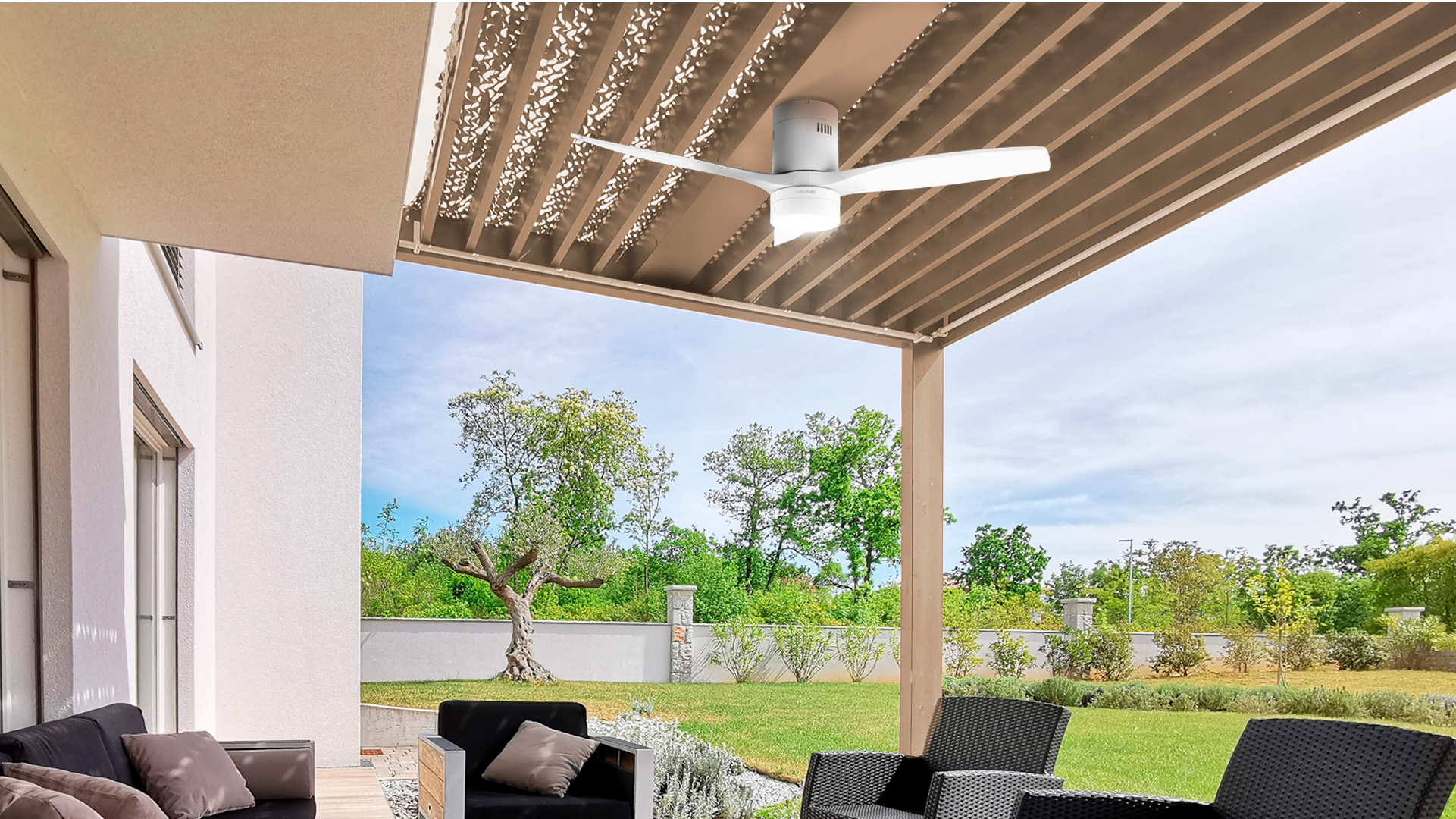 Escena al aire libre con ventilador, pérgola y casa en un día soleado.