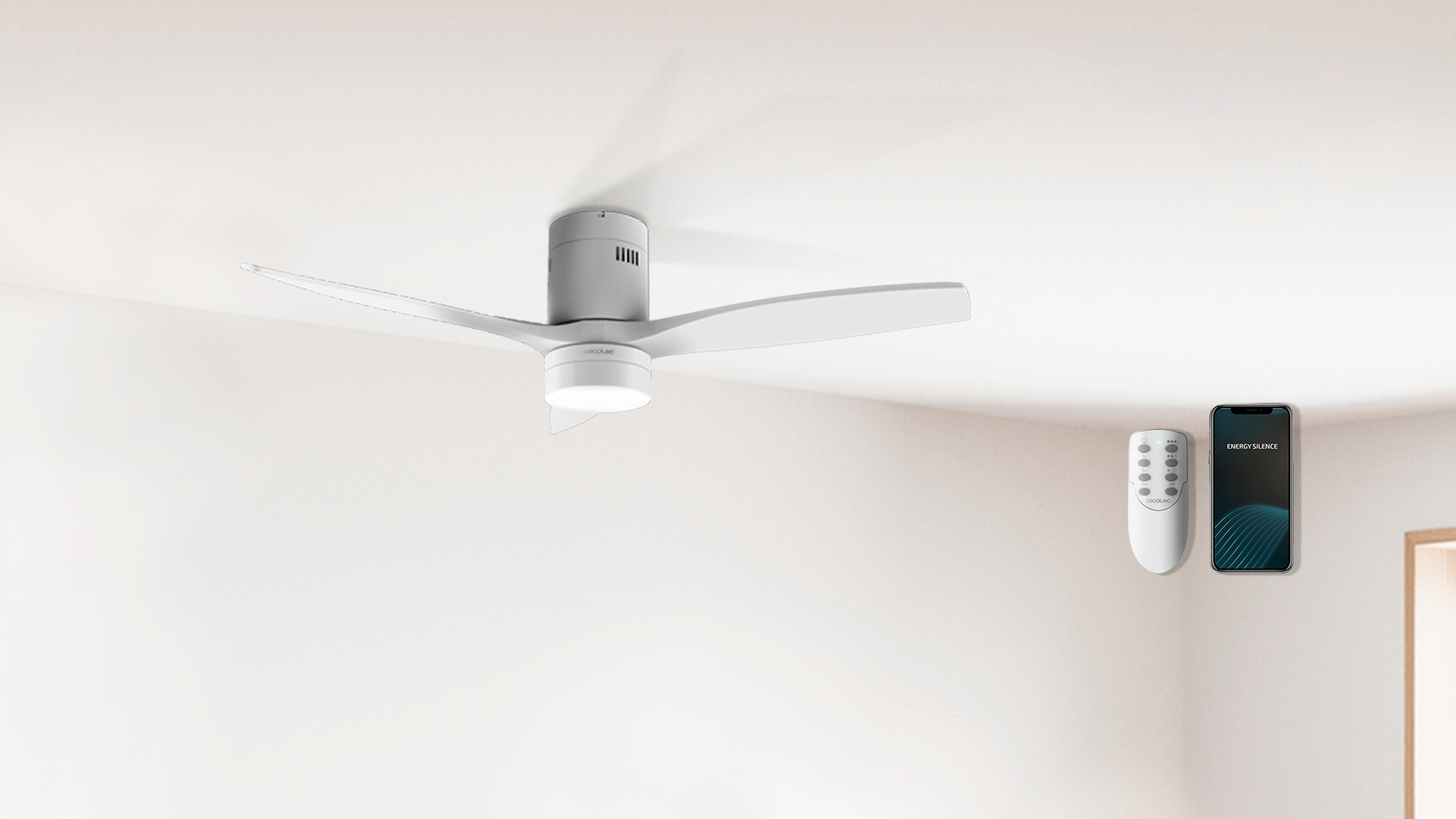 Ventilador de techo blanco con tres aspas, mando y smartphone en pared blanca.