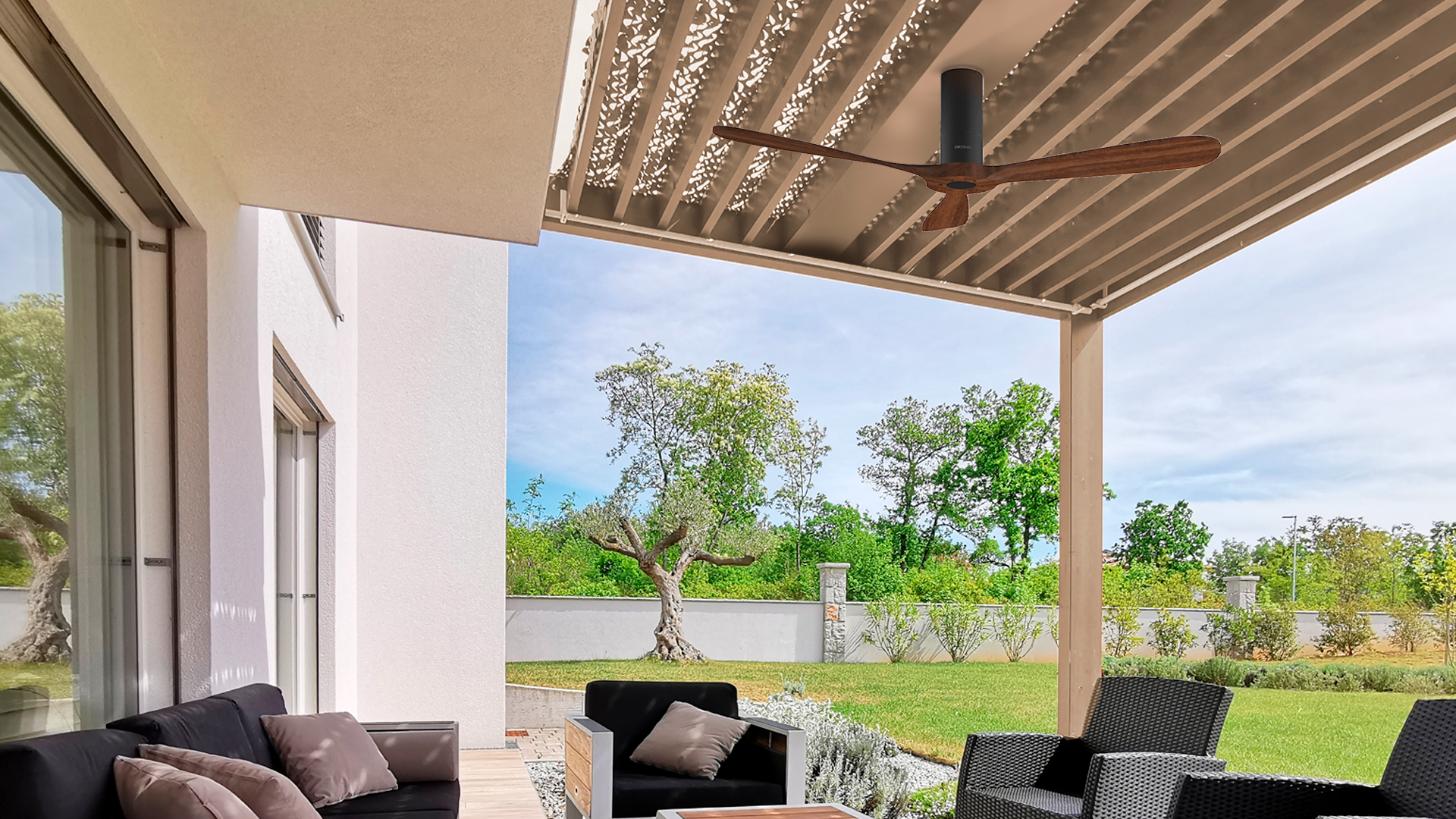 Un patio al aire libre moderno con ventilador de techo, plantas y vista de los árboles.