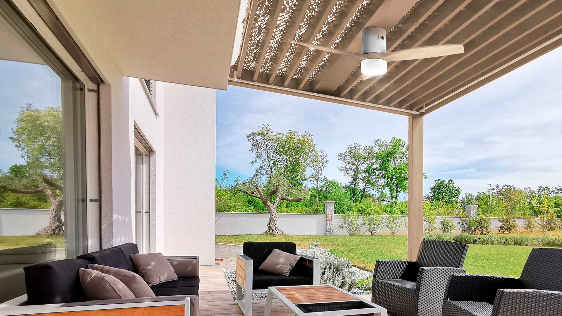 Escena de patio al aire libre. Casa blanca, árboles y muebles de exterior, incluido un ventilador de techo.