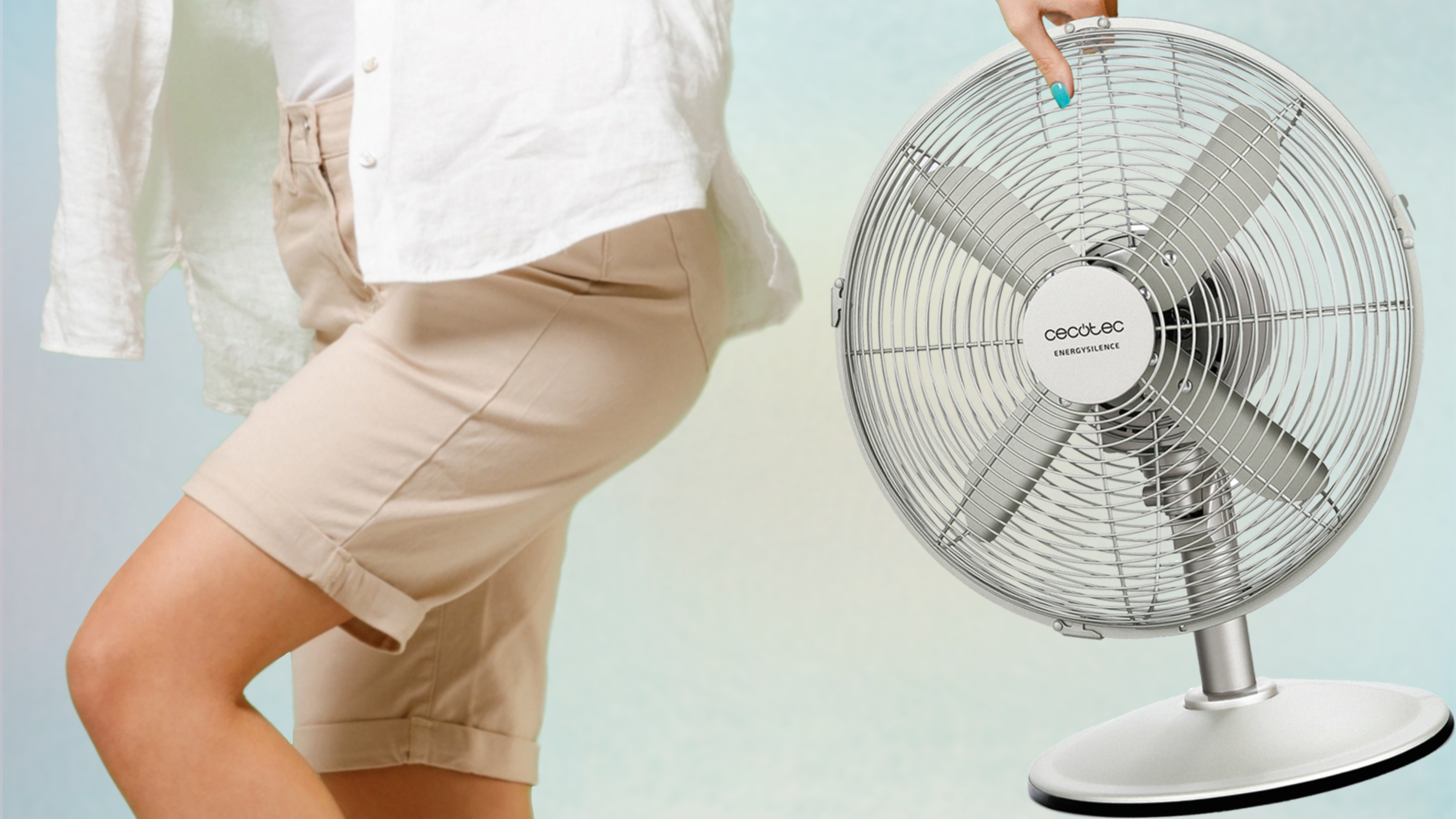 Persona sosteniendo ventilador, con pantalones cortos y fondo azul claro.