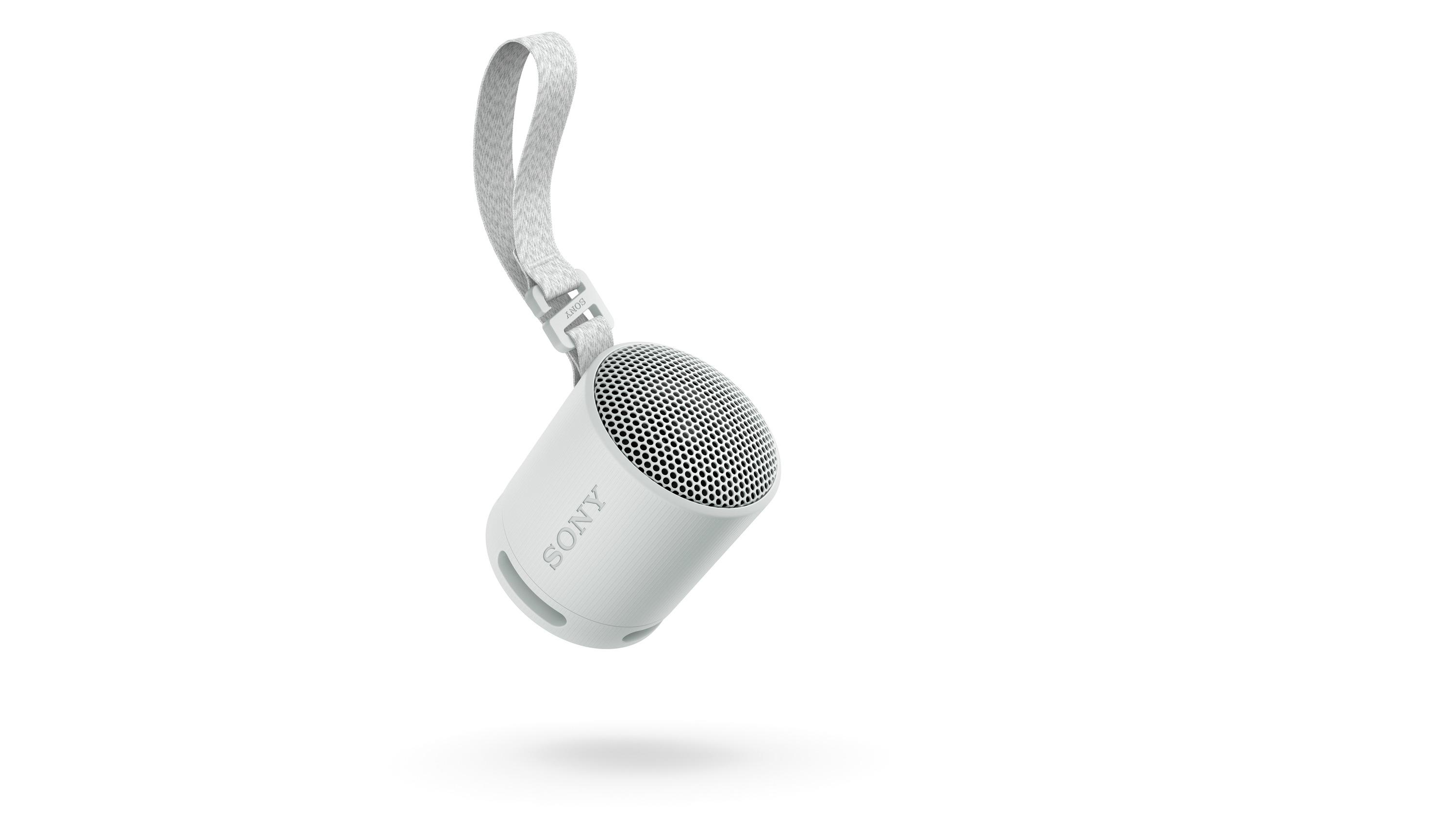 Ein weißer tragbarer Sony-Lautsprecher mit Riemen, vor weißem Hintergrund angewinkelt.