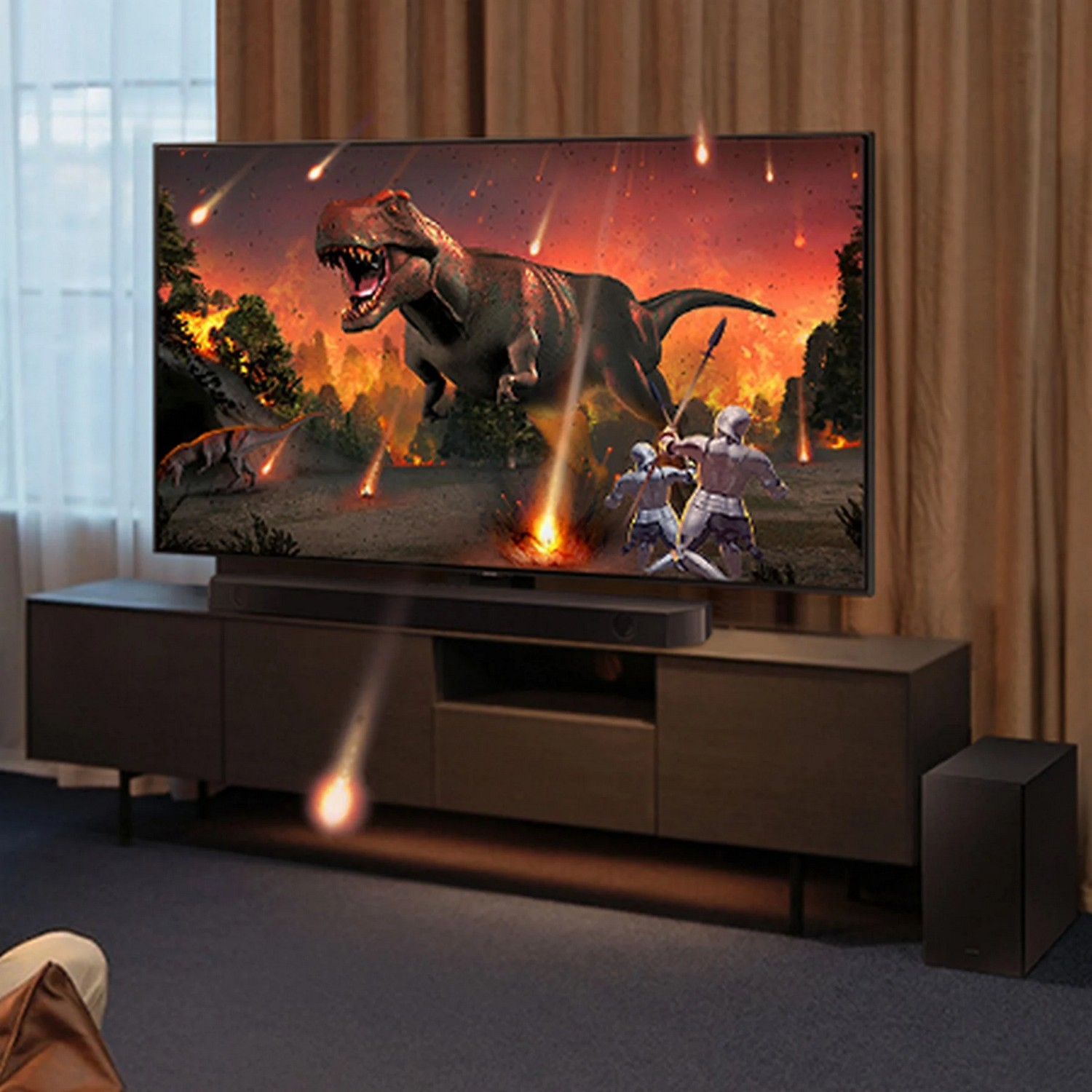 Un grand téléviseur montre une scène de dinosaures. Une barre de son et un caisson de basses sont placés sur un meuble en bois foncé.
