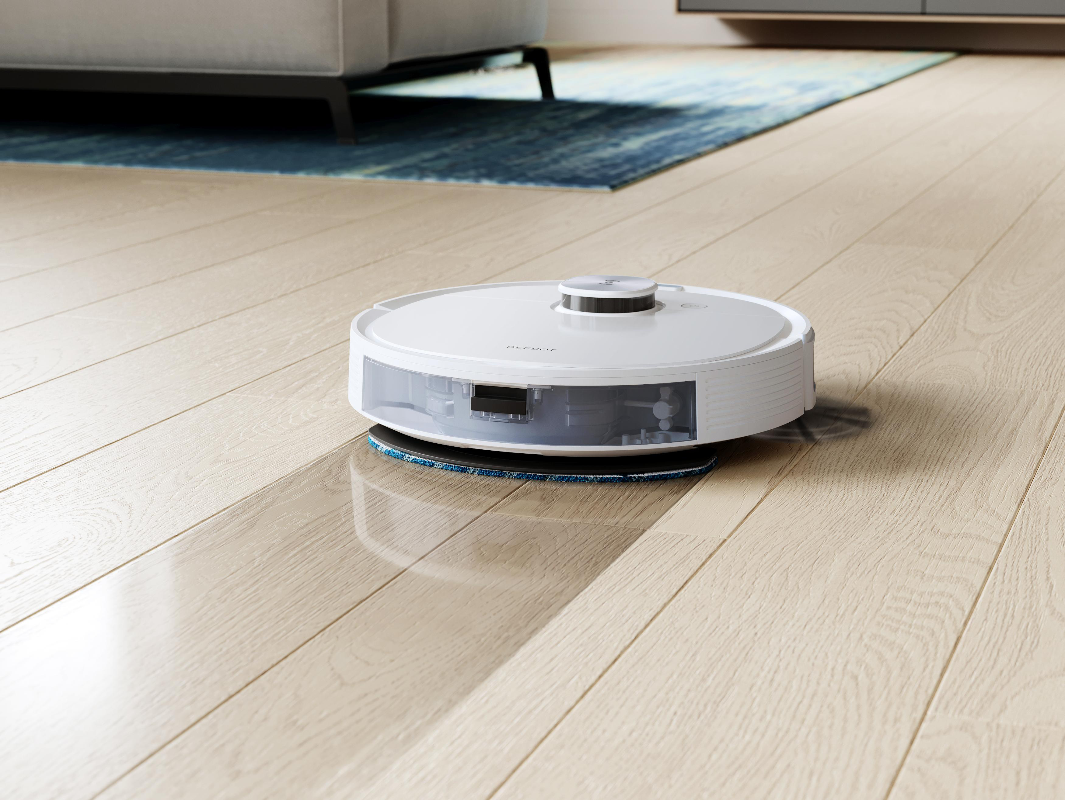 Ein weißer Roboter-Staubsauger auf einem Holzboden beim Reinigen.