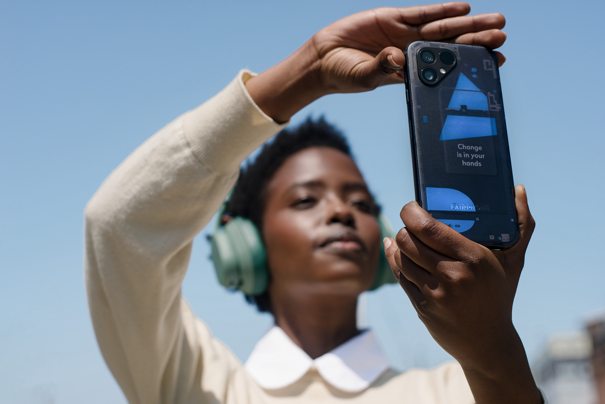 Frau hält Handy, macht Selfie. Telefon zeigt digitalen Bildschirm mit Text: "Change is in your hands".