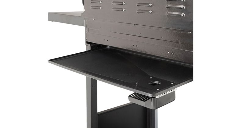 Fekete grill oldala. Fém felület. Egy kis tartály alul. Fehér háttér.