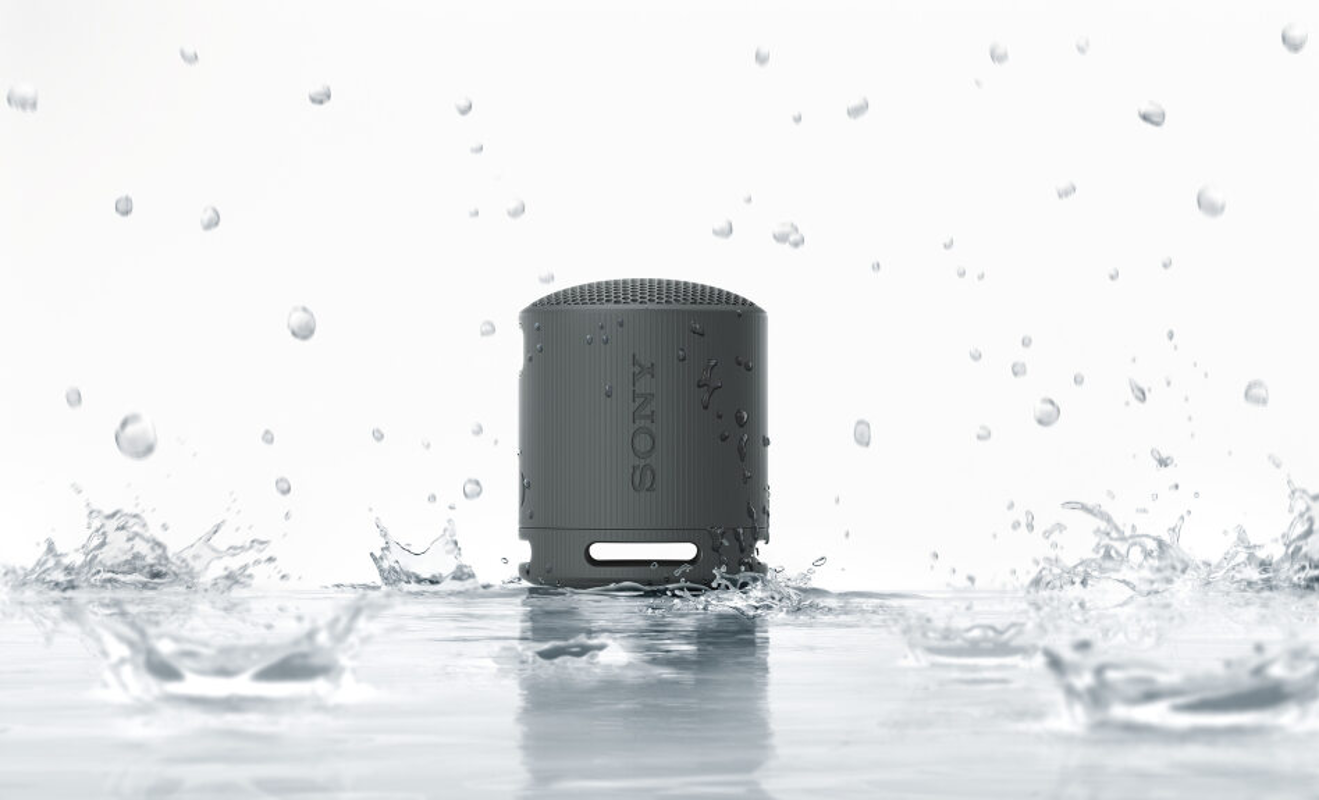 Grauer, wasserdichter Sony-Lautsprecher im Wasser. Wasser spritzt um den Lautsprecher herum.