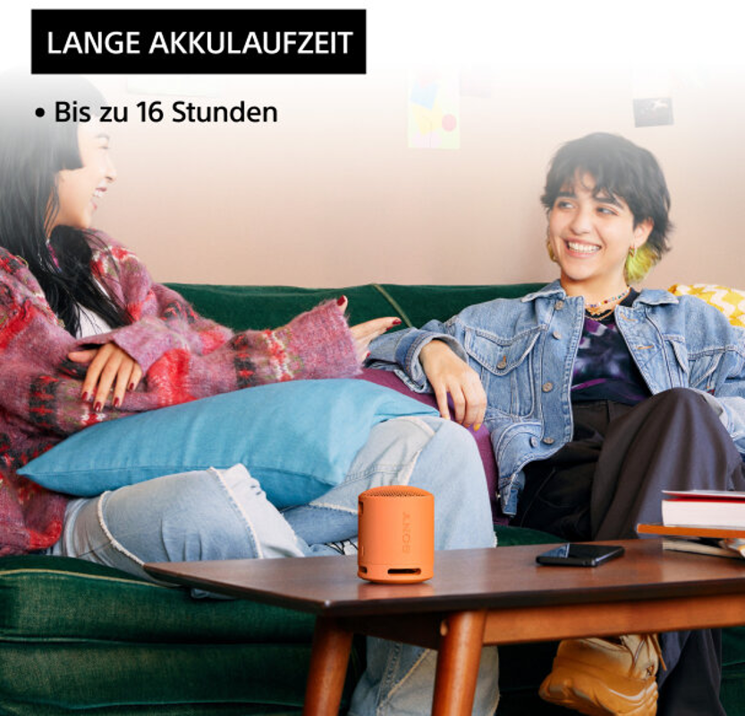Deux femmes souriantes, une avec un haut-parleur orange sur la table, texte en haut.