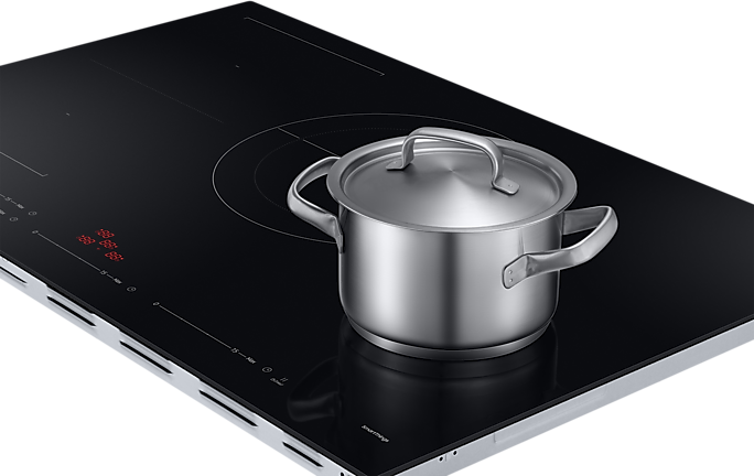 Black induction cooktop with a stainless steel pot on it, close-up shot.