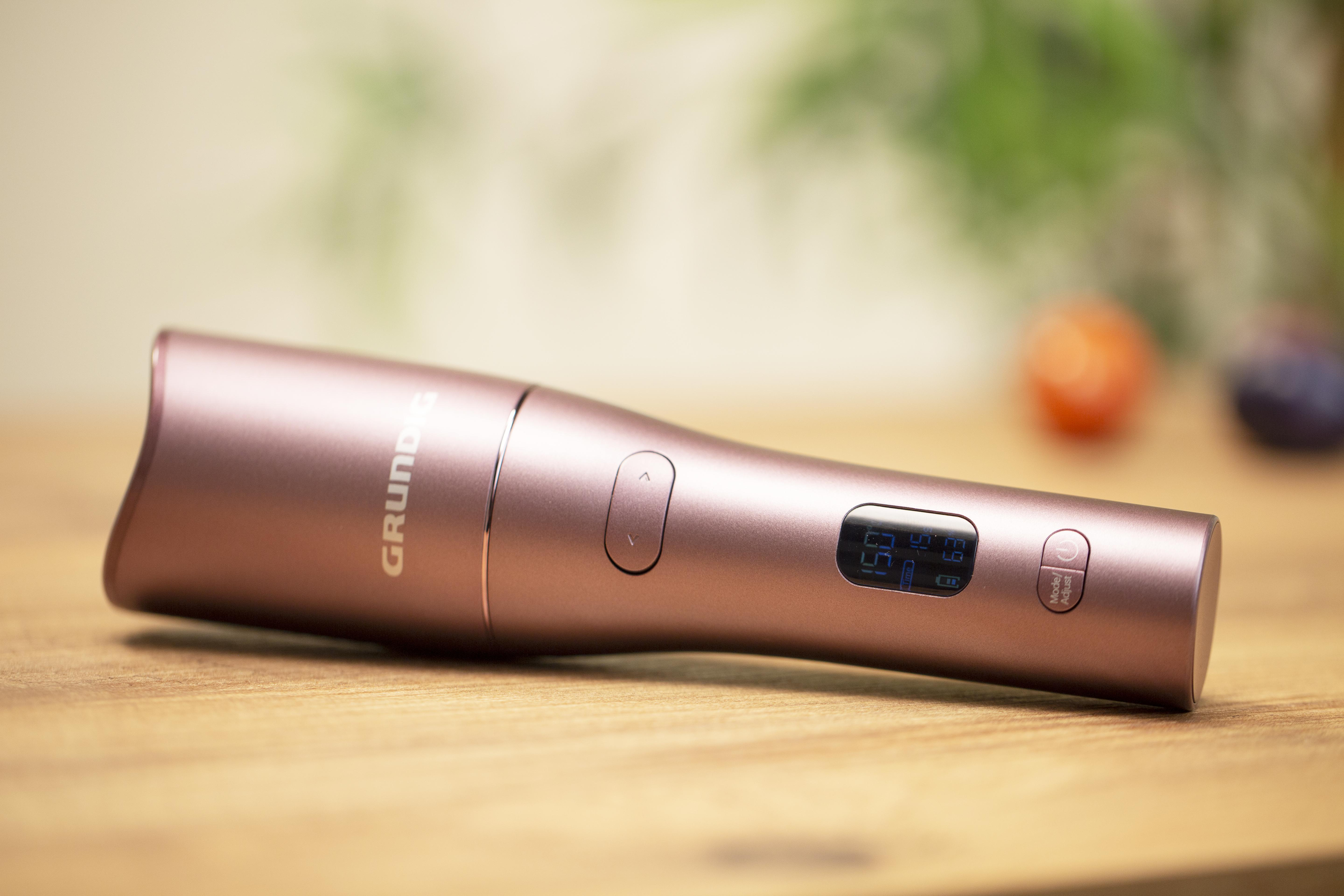 Ein roségoldenes Grundig-Gerät auf einem Holztisch mit unscharfem Hintergrund.