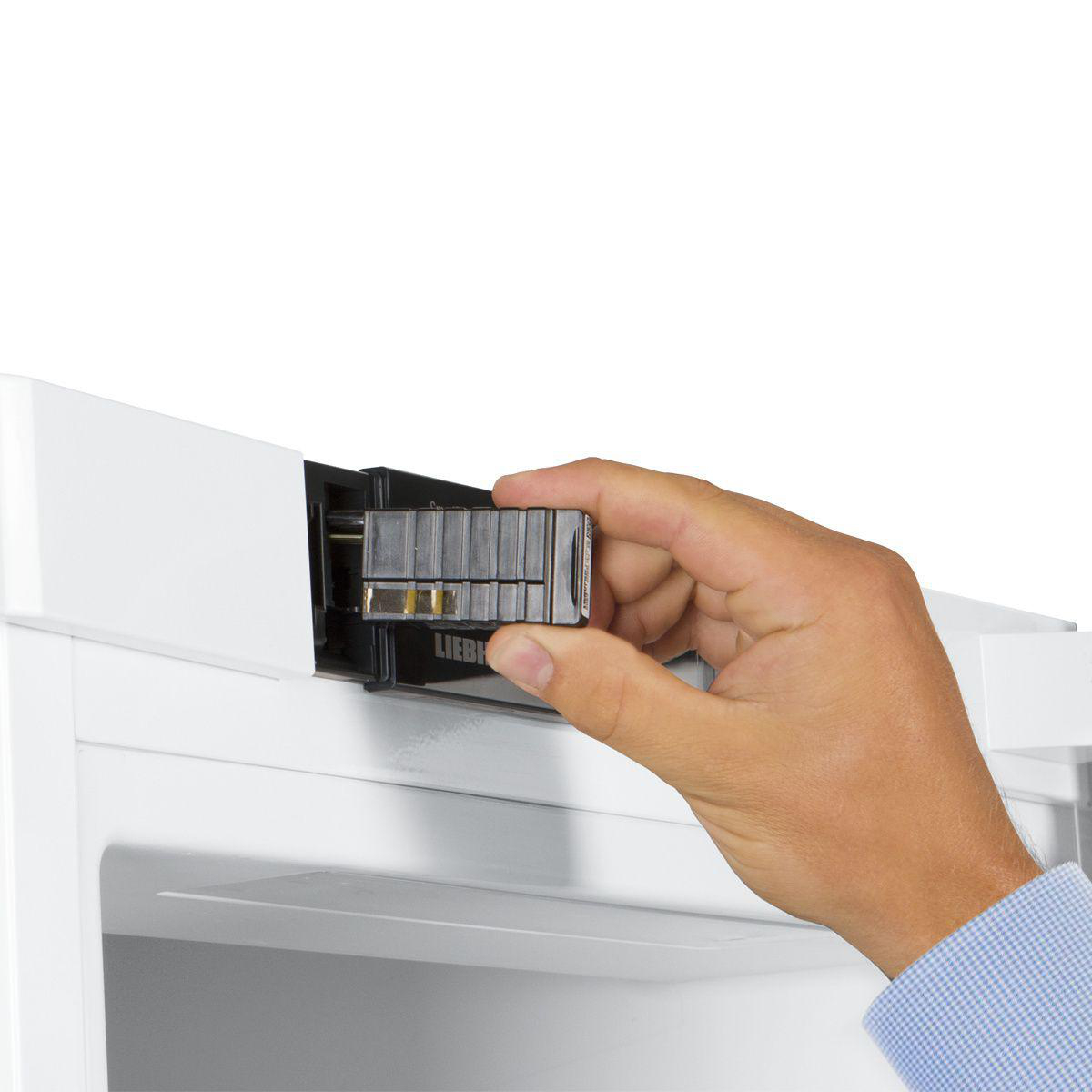 Hand setzt schwarze Komponente in weißen Kühlschrank ein. Marke Liebherr.