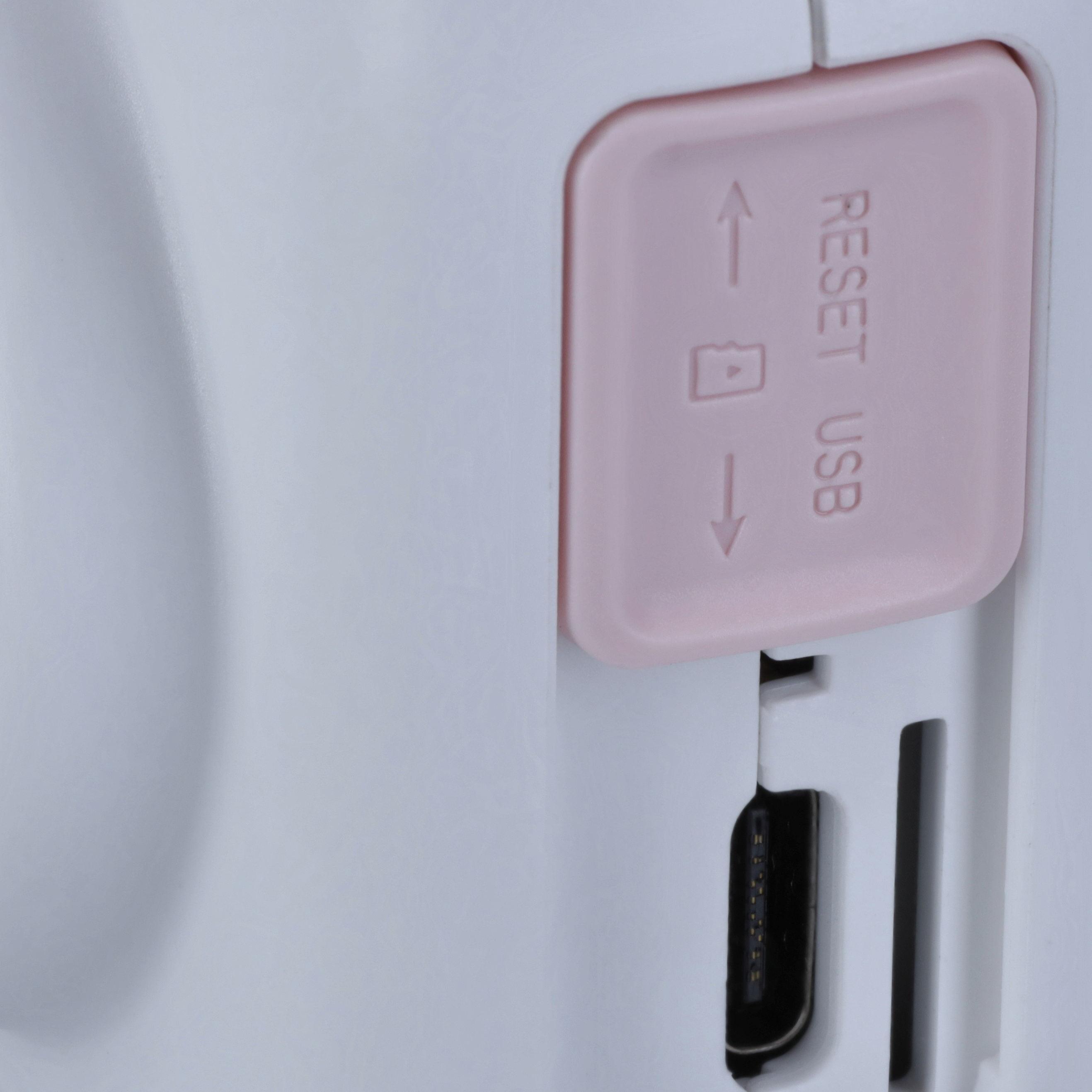 Nahaufnahme der Seitenwand eines Geräts mit rosa Reset-Taste und USB-Anschluss.