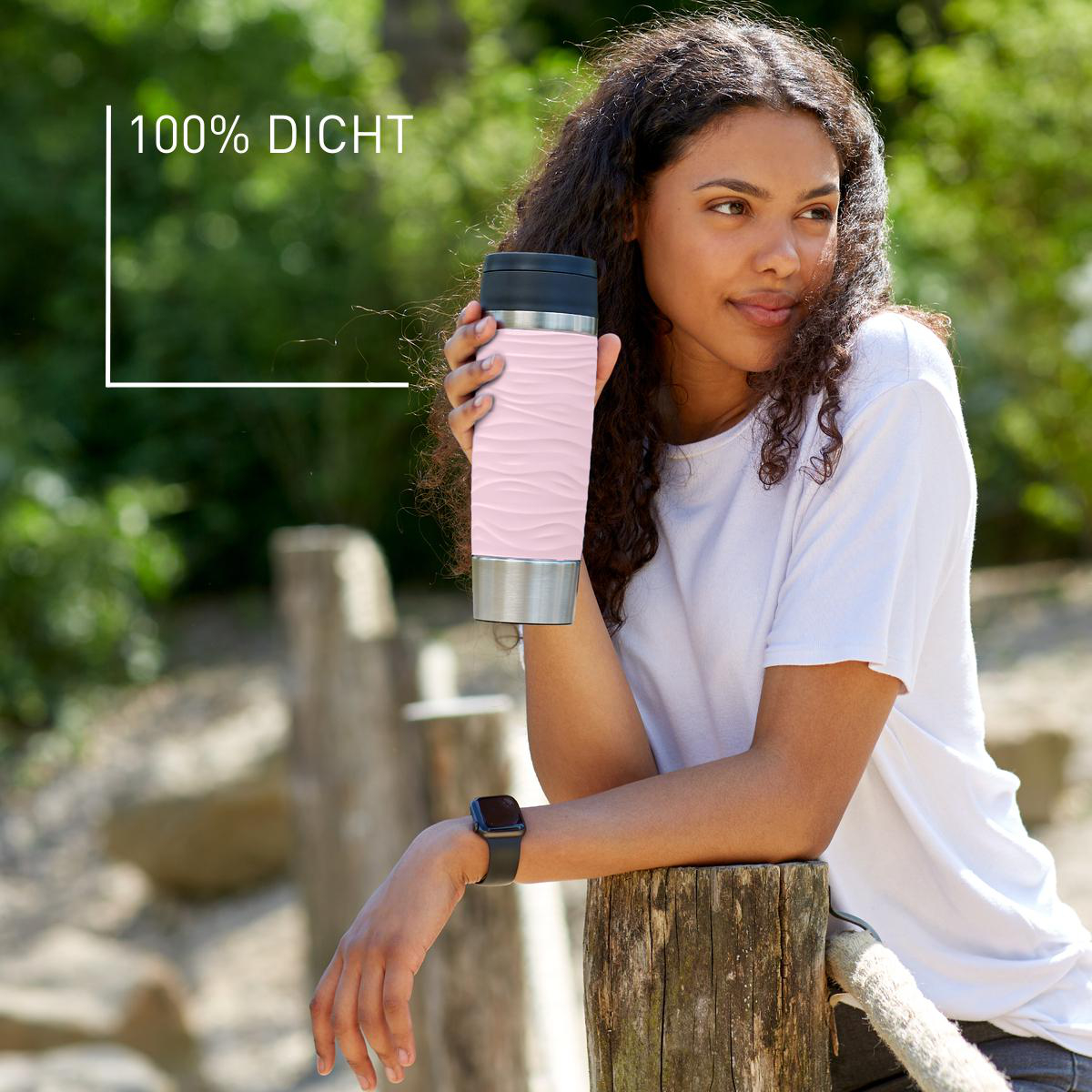 Frau hält einen rosa-silbernen Becher. Der Text sagt 100% Dicht.
