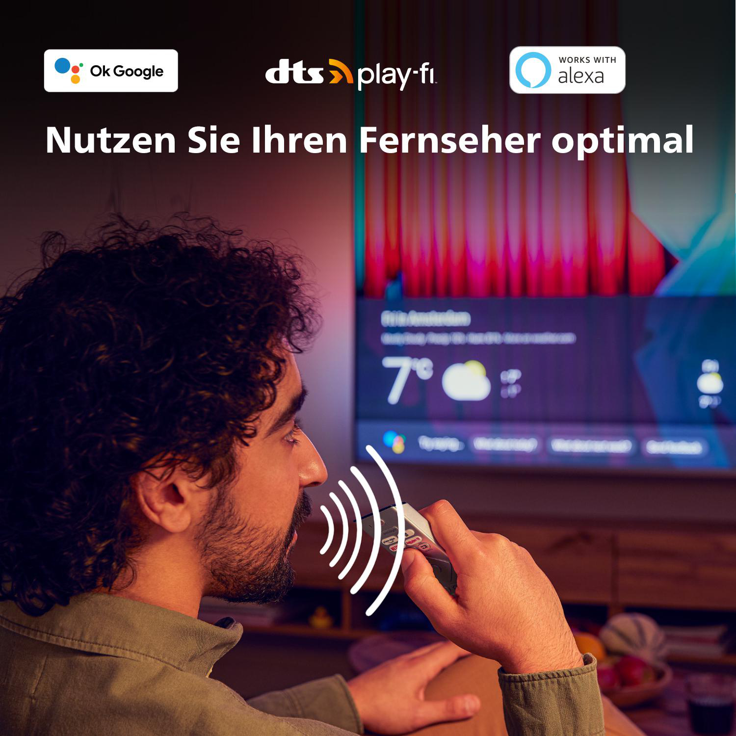 Mann verwendet Sprachsteuerung mit Fernbedienung. Fernsehbildschirm zeigt Informationen. Der Raum ist beleuchtet.