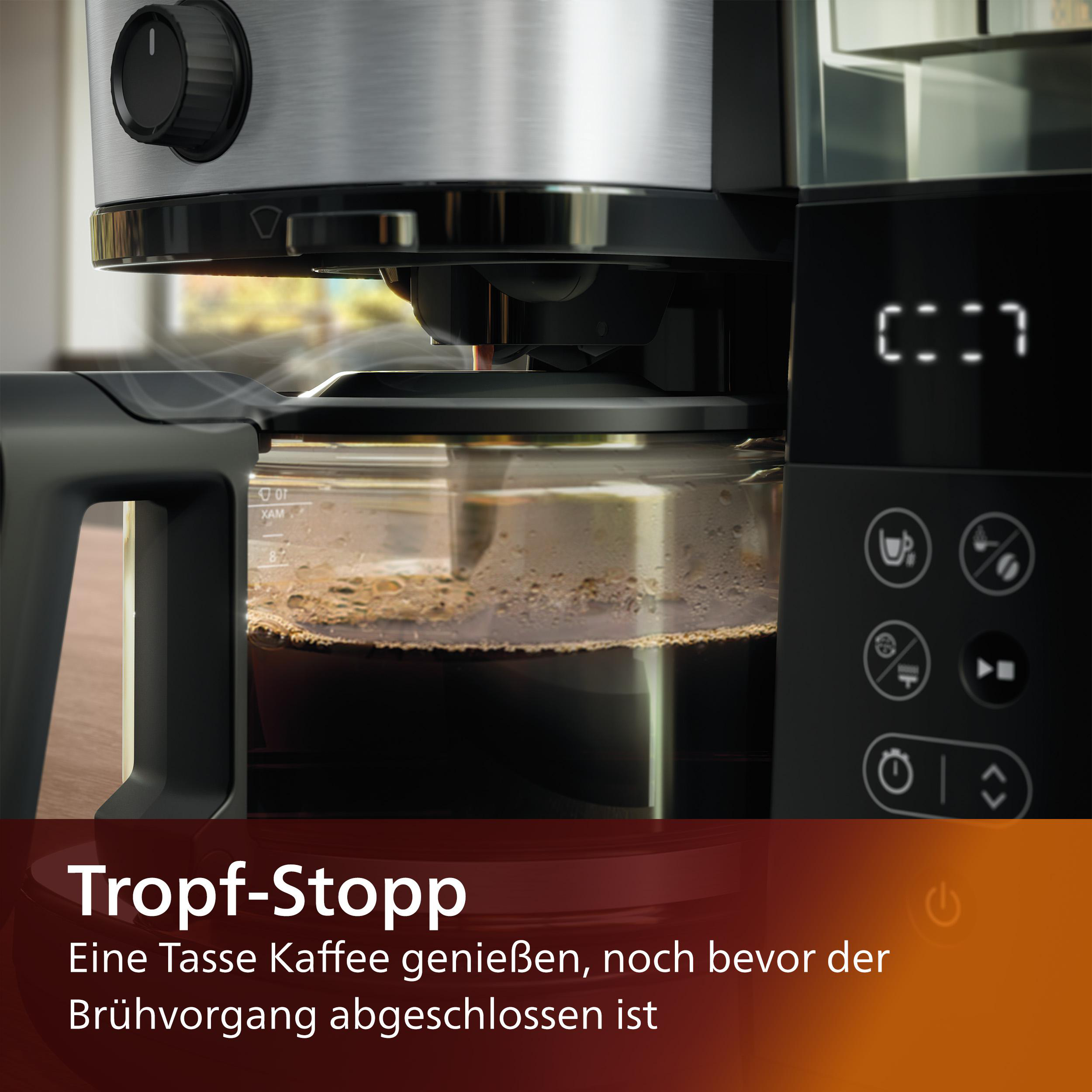 Kaffeemaschine beim Brühen von Kaffee. Etwas Dampf ist sichtbar. Digitaluhr rechts.